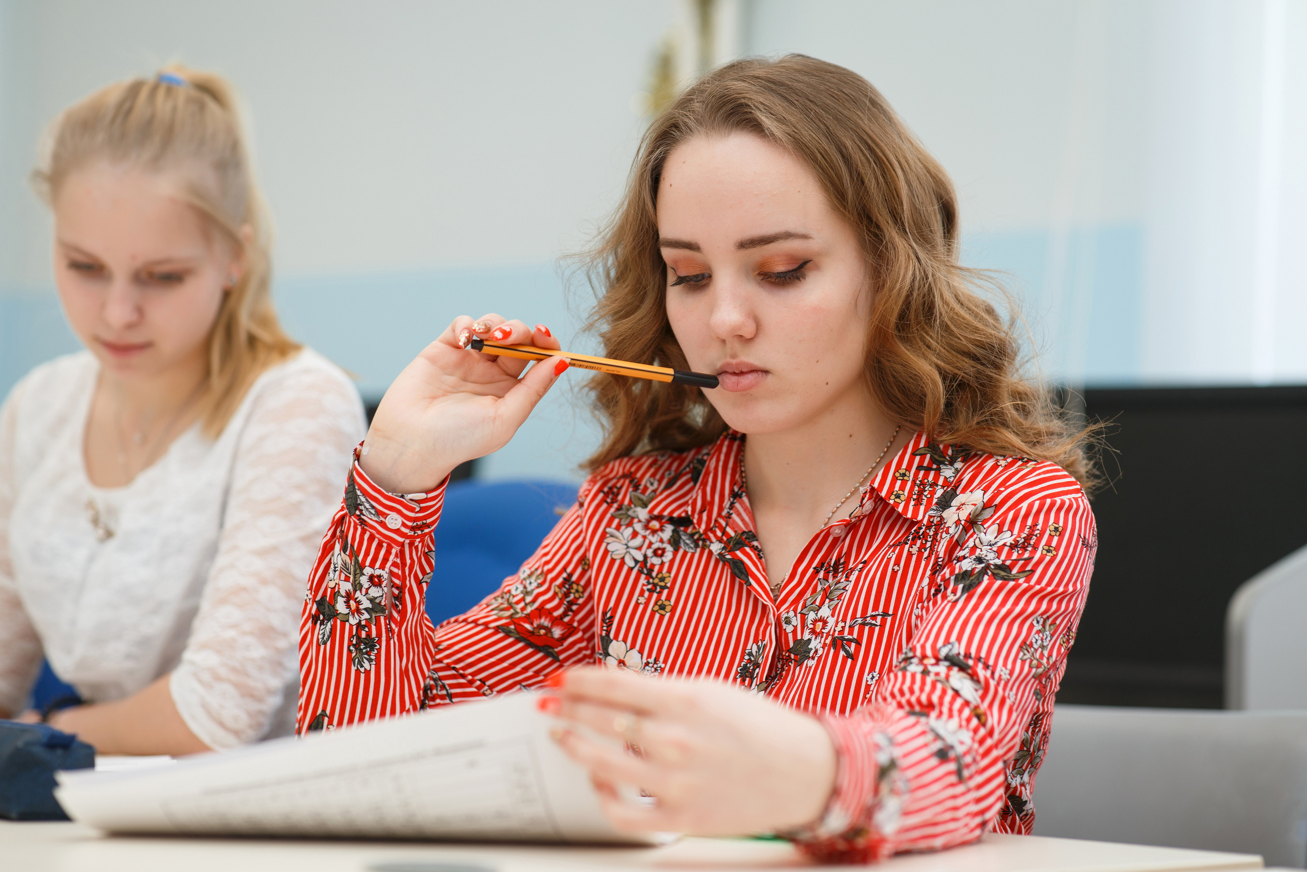 Старшеклассница задумчиво изучает задание в учебном пособии