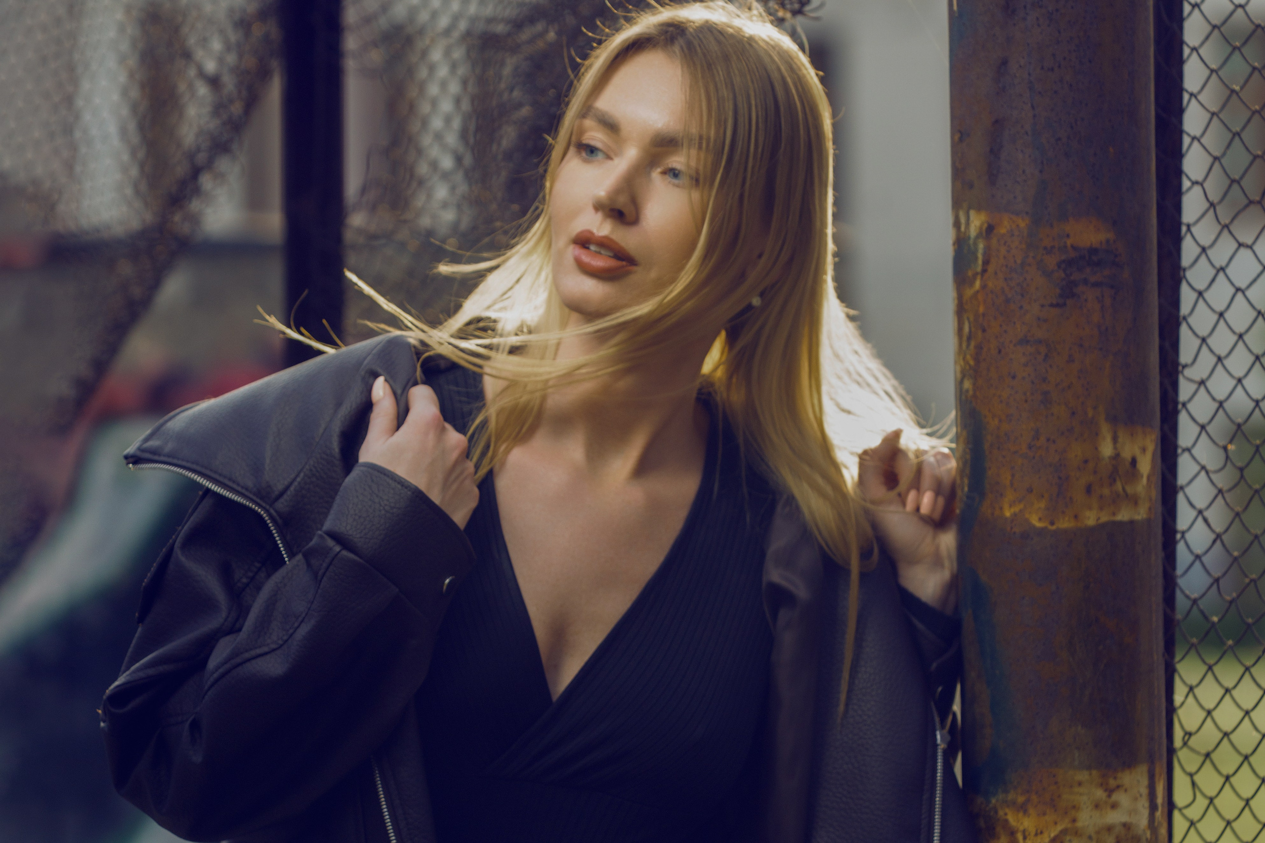 Портрет в стиле street-style: девушка в кожаной куртке на фоне граффити и металлических конструкций.