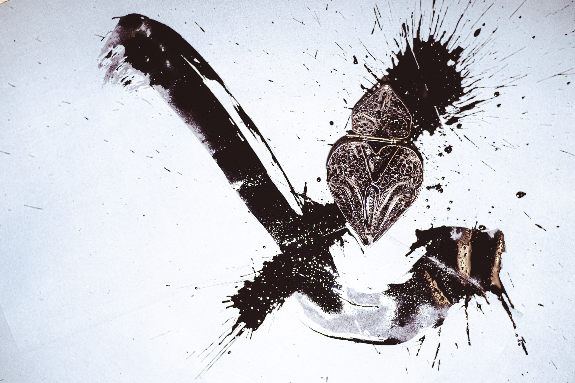 Вид сверху. Каллиграфия в виде буквы Х, черный кулон в форме сердца в чернилах