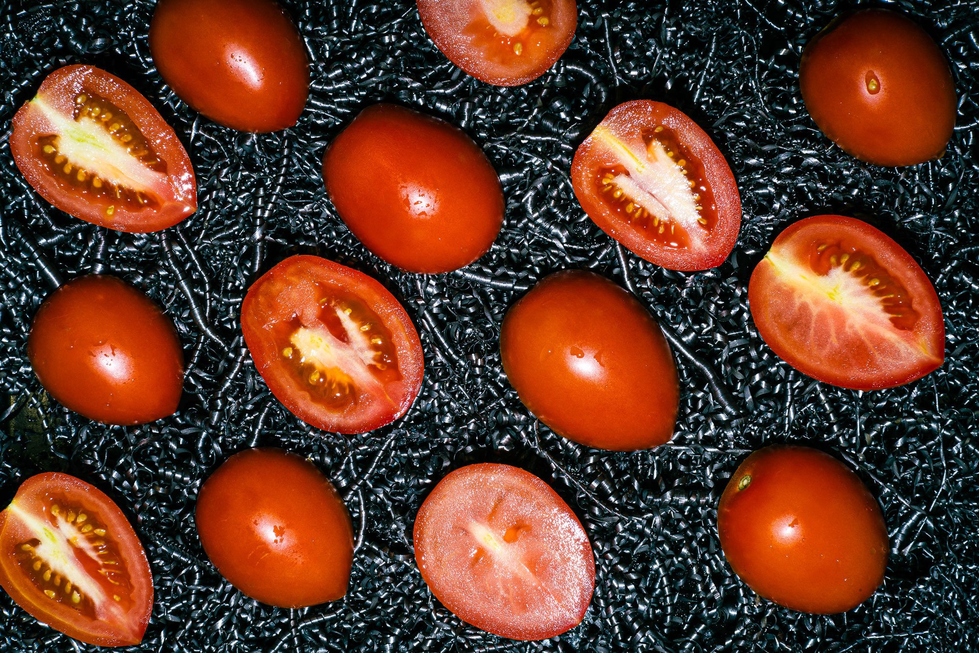 Вид сверху. Фон из металлической стружки. красные помидоры разрезаны и выложенные вдоль кадра 