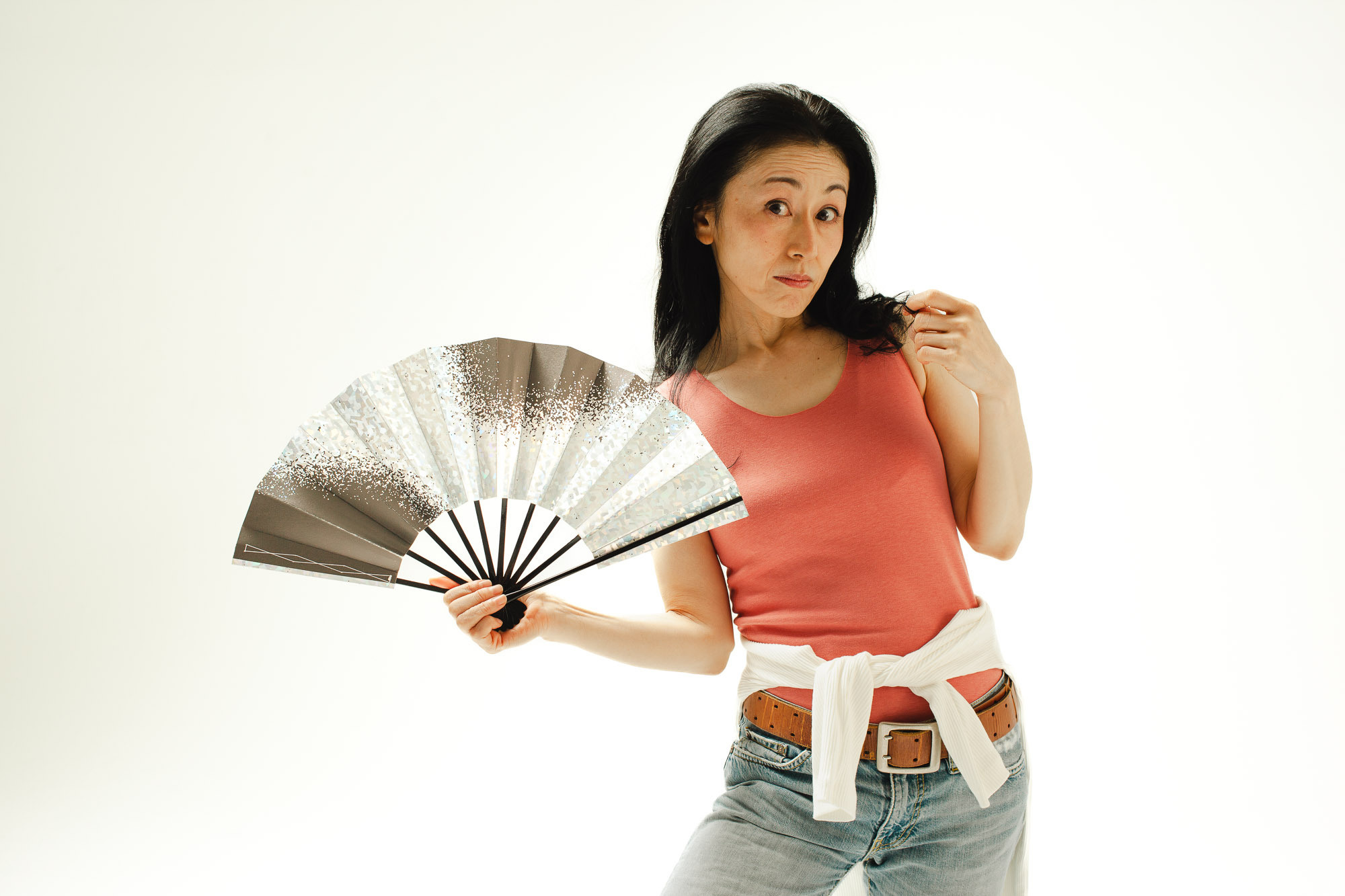 Белый фон, японская актриса средних лет, веер раскрыт в сторону камеры, загадочное настроение