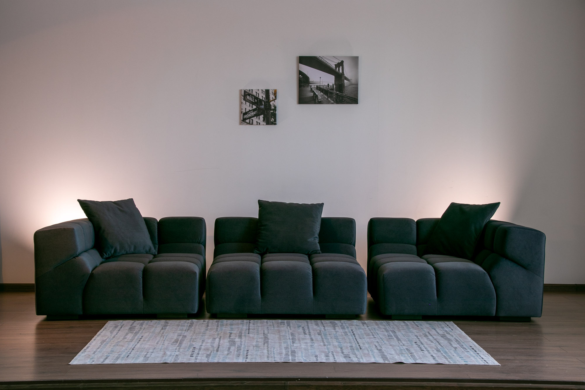 Крупный черный диван, три секции, в белом интерьере и приглушенным вечерним свете