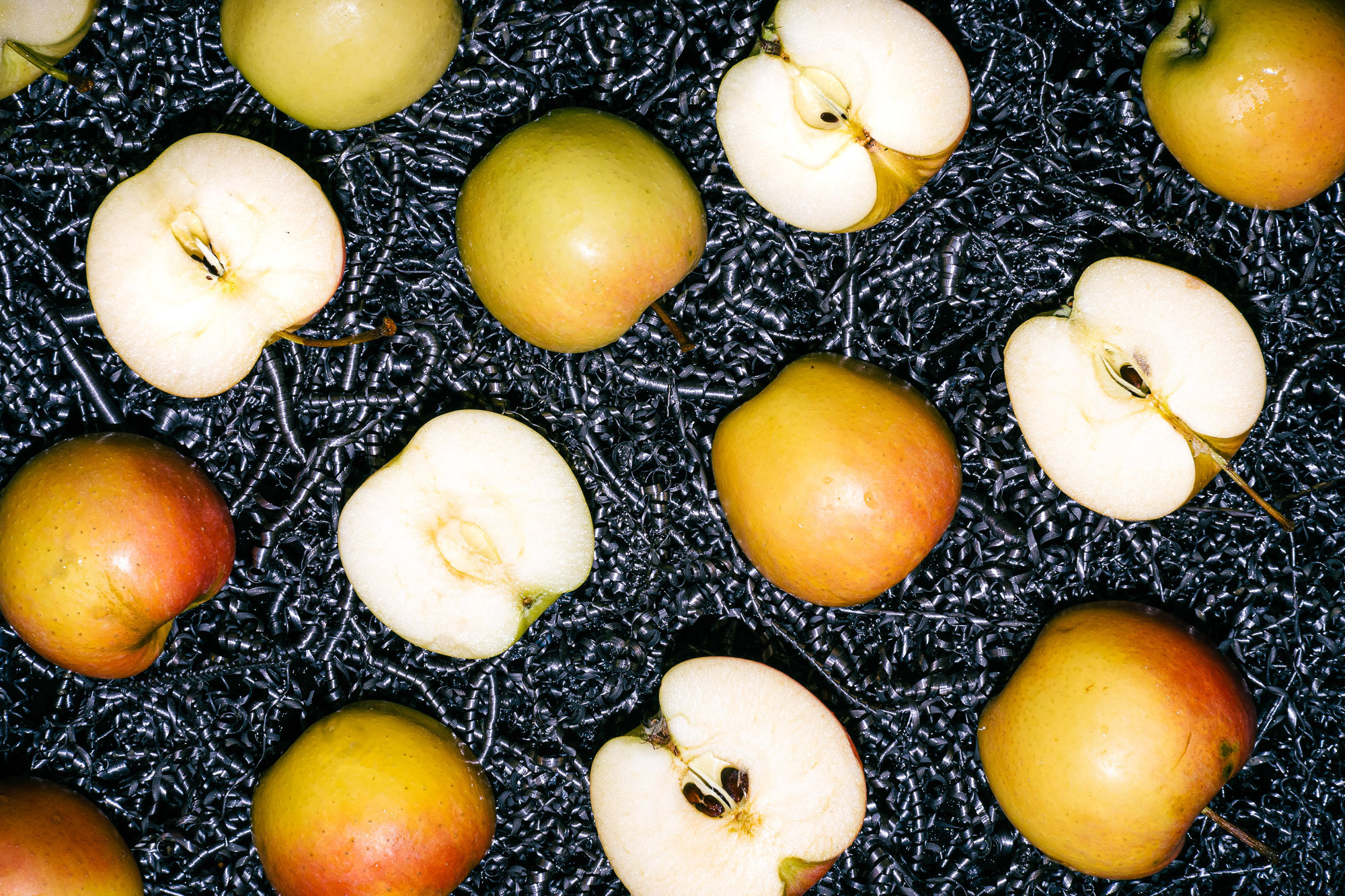 Вид сверху. Фон из металлической стружки. Желтые и красные сезонные яблоки разрезаны и выложены вдоль кадра 