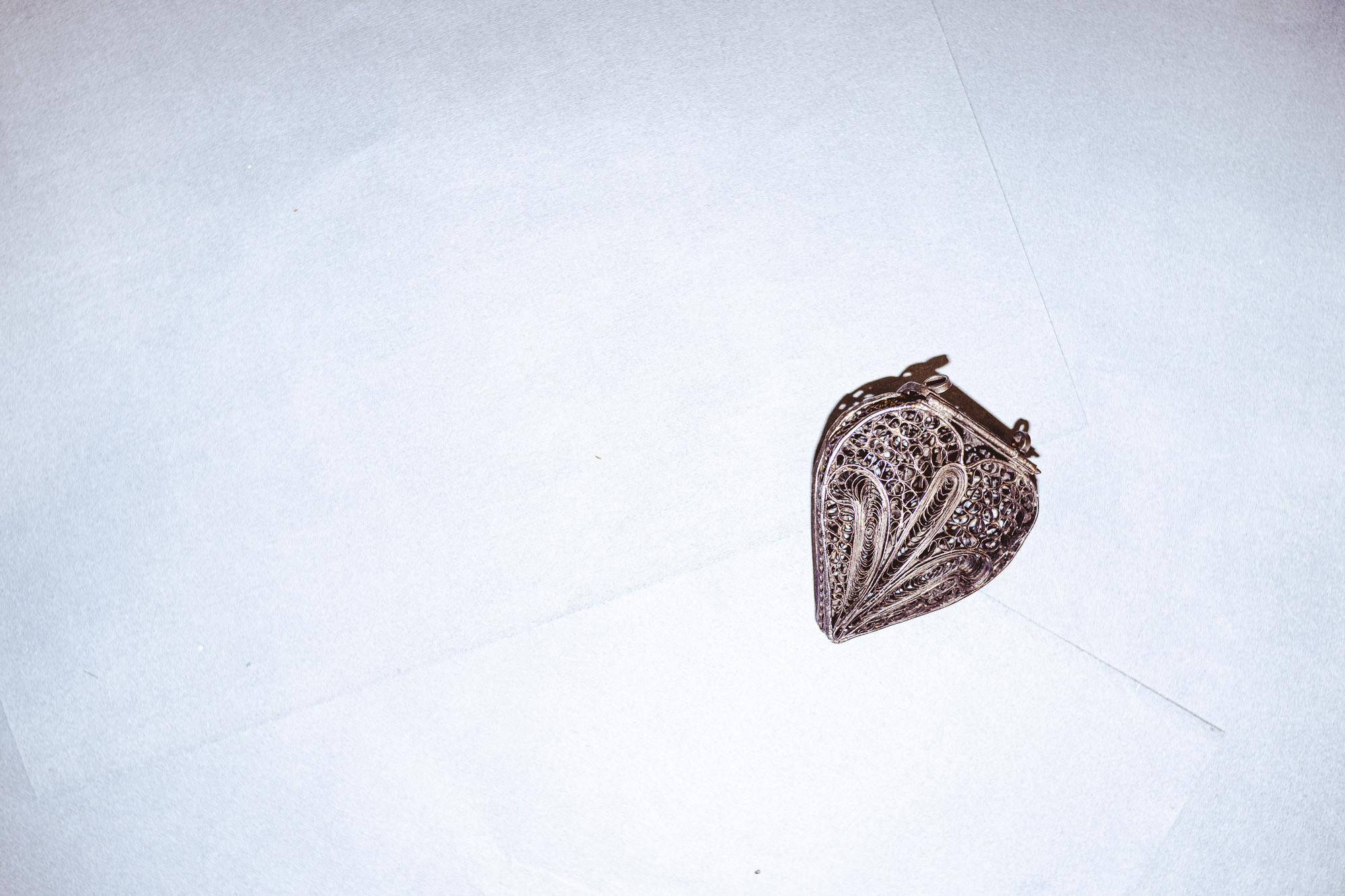 Вид сверху. Черный кулон на белом фоне, вспышка яркая