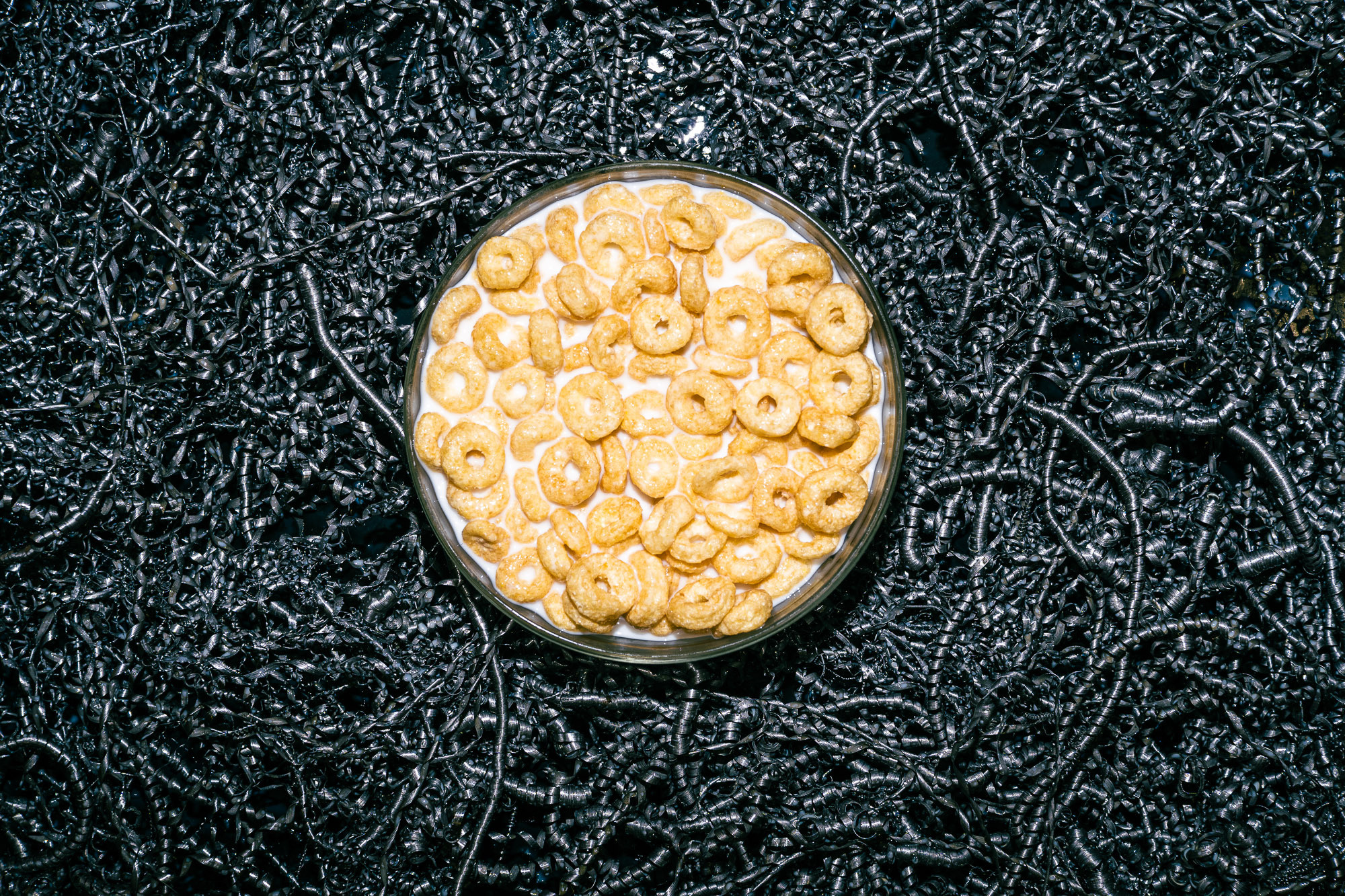 Вид сверху. Фон из металлической стружки. Круглое блюдо. Кукурузные колечки залиты молоком