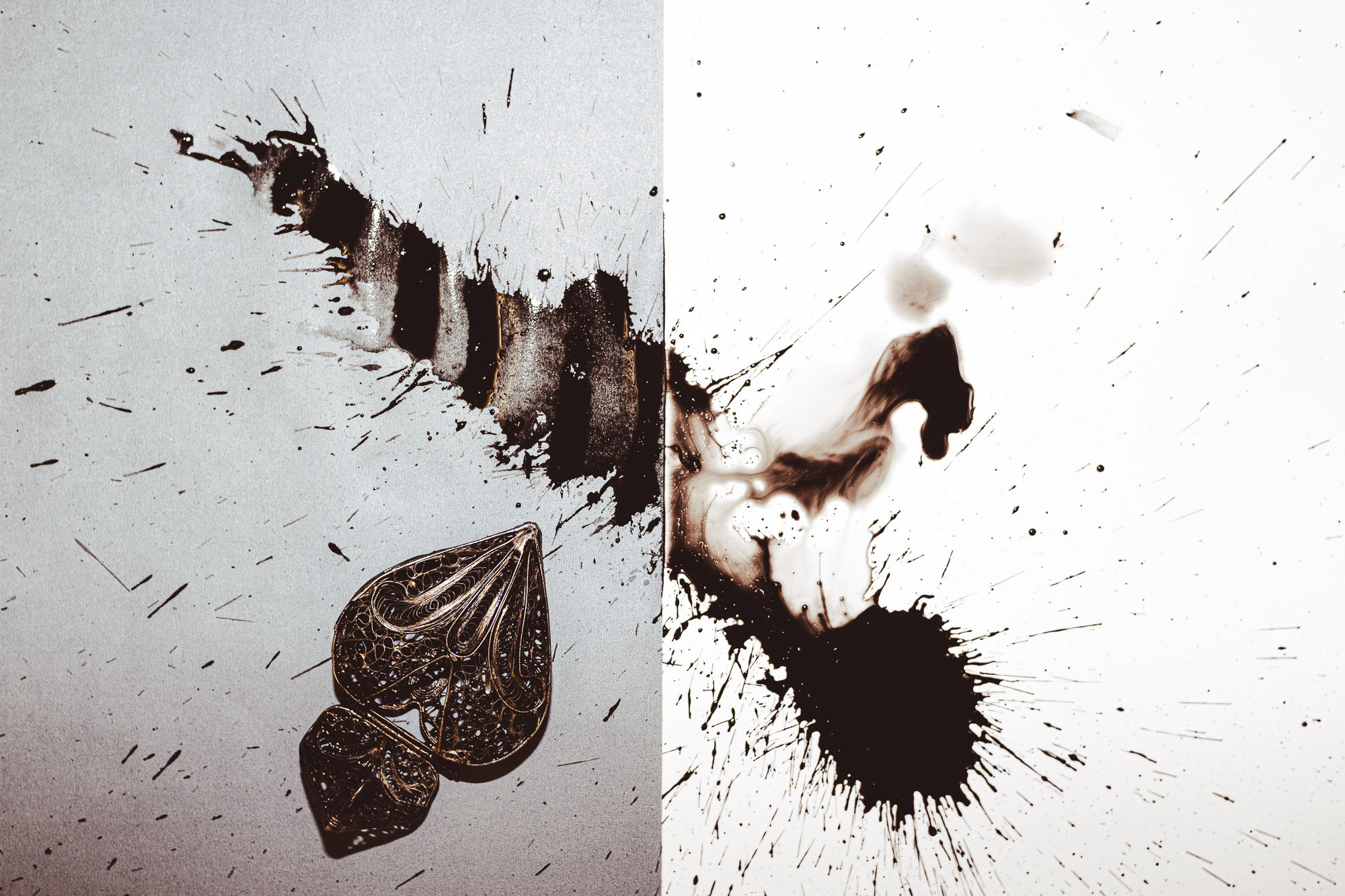 Вид сверху. Фон разделен на две половинки. Белый и серый фон. Толстая линия от чернил. Кулон в форме сердца в пятнах от чернил