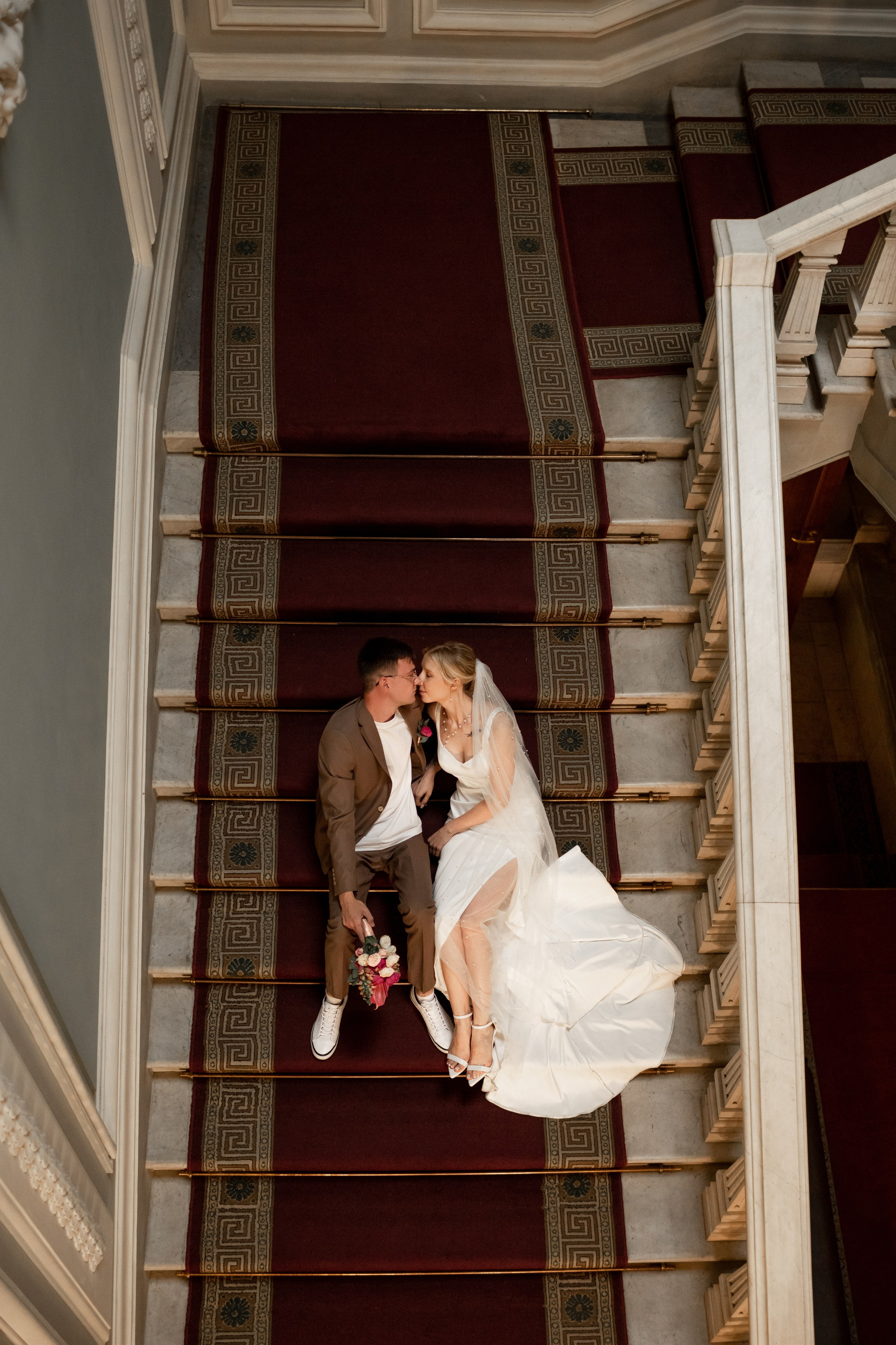 Жених и невеста лежат на красивой лестнице во дворце.