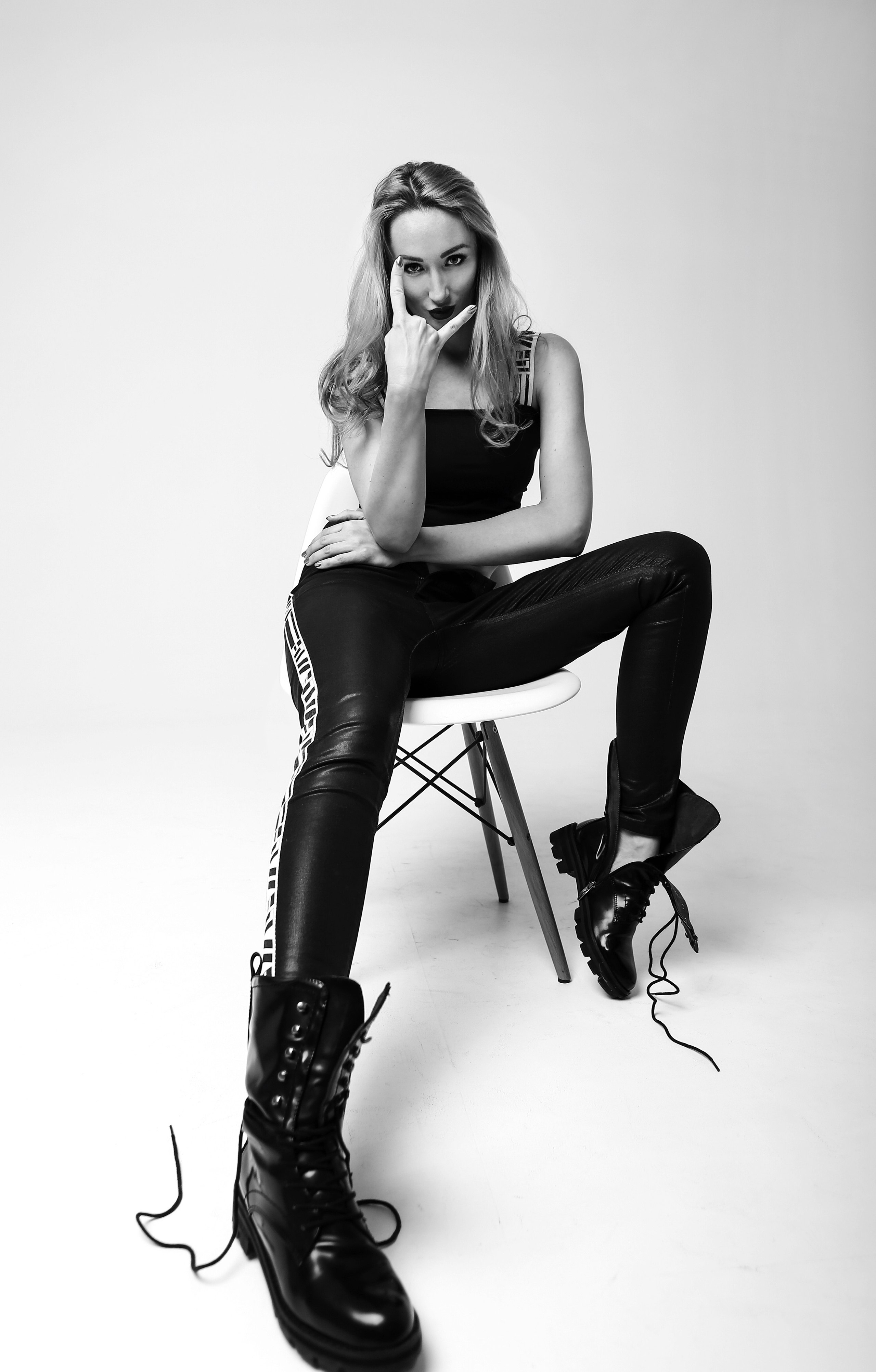 На стуле в студии сидит девушка в грубых ботинках