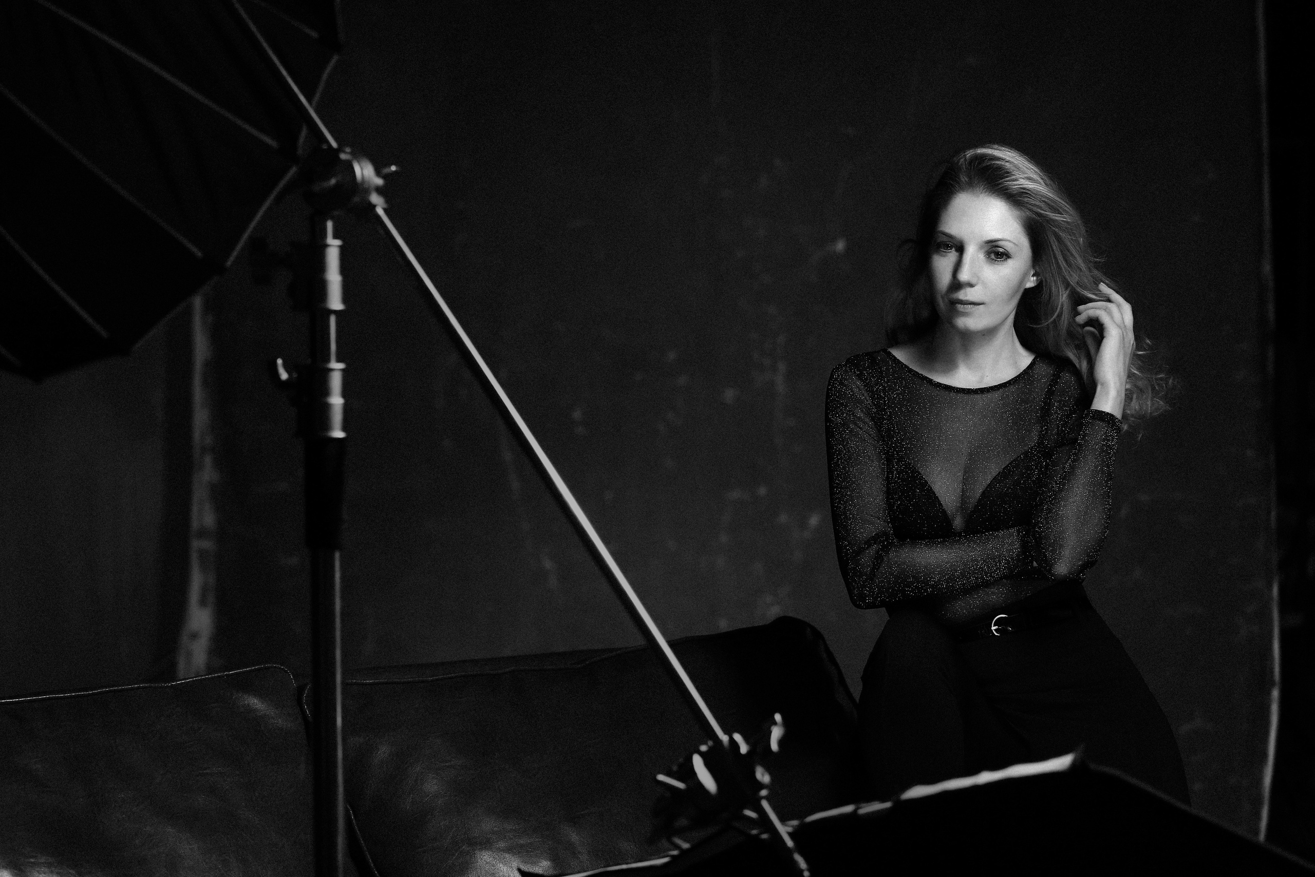 Девушка в фотостудии сидит на кожаном диване