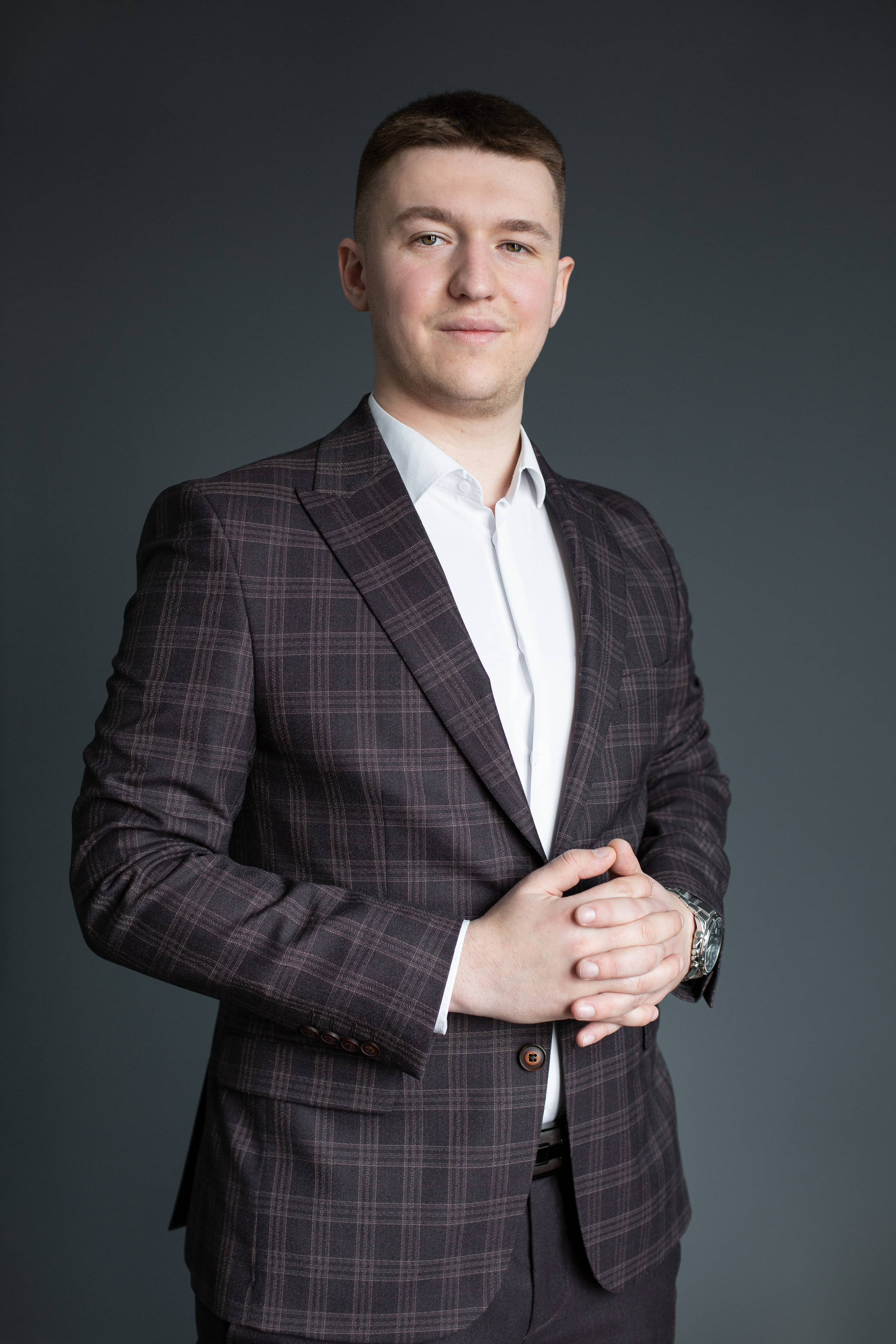 Парень позирует на фоне серой стены