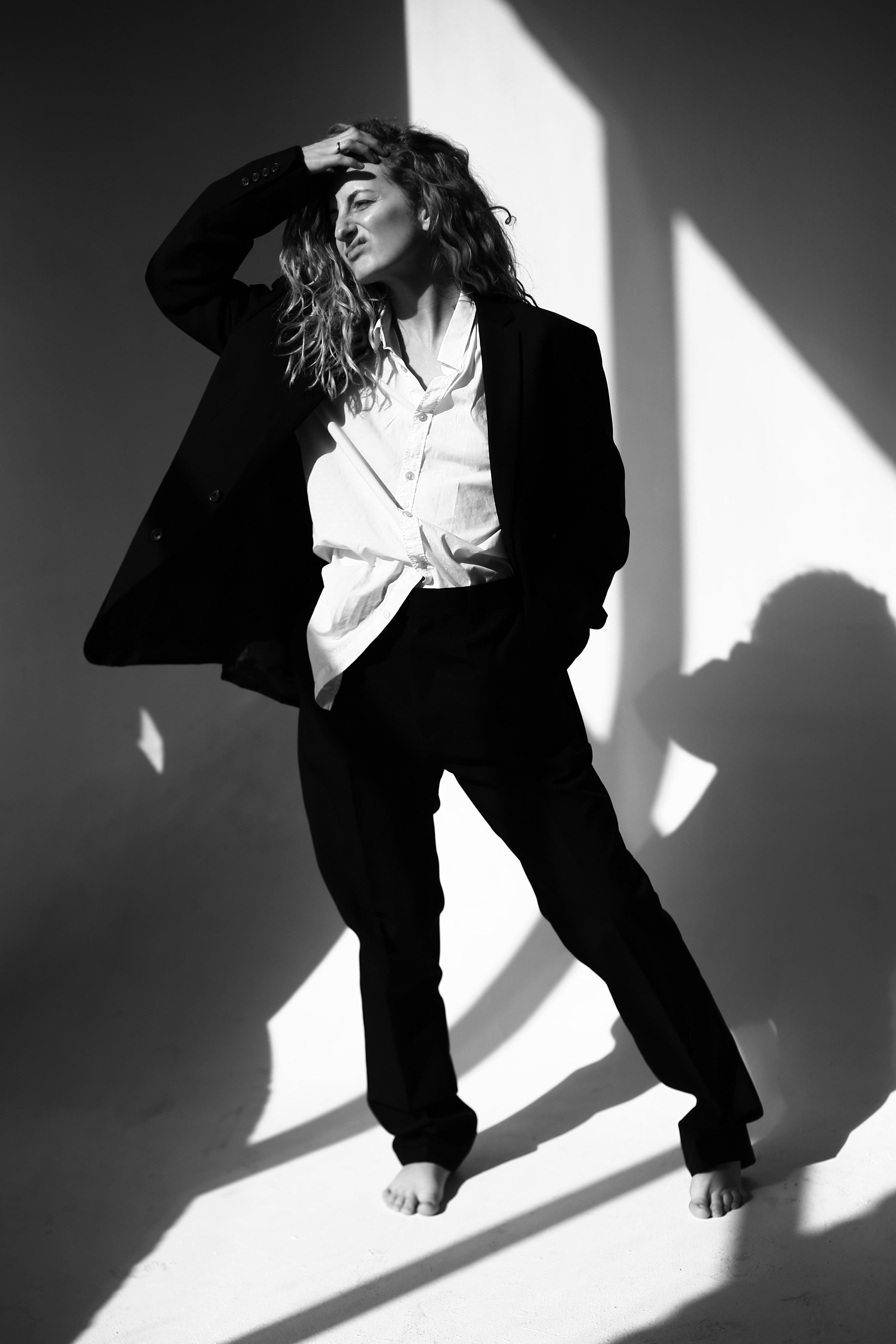 Кудрявые волосы у девушки в брючном костюме