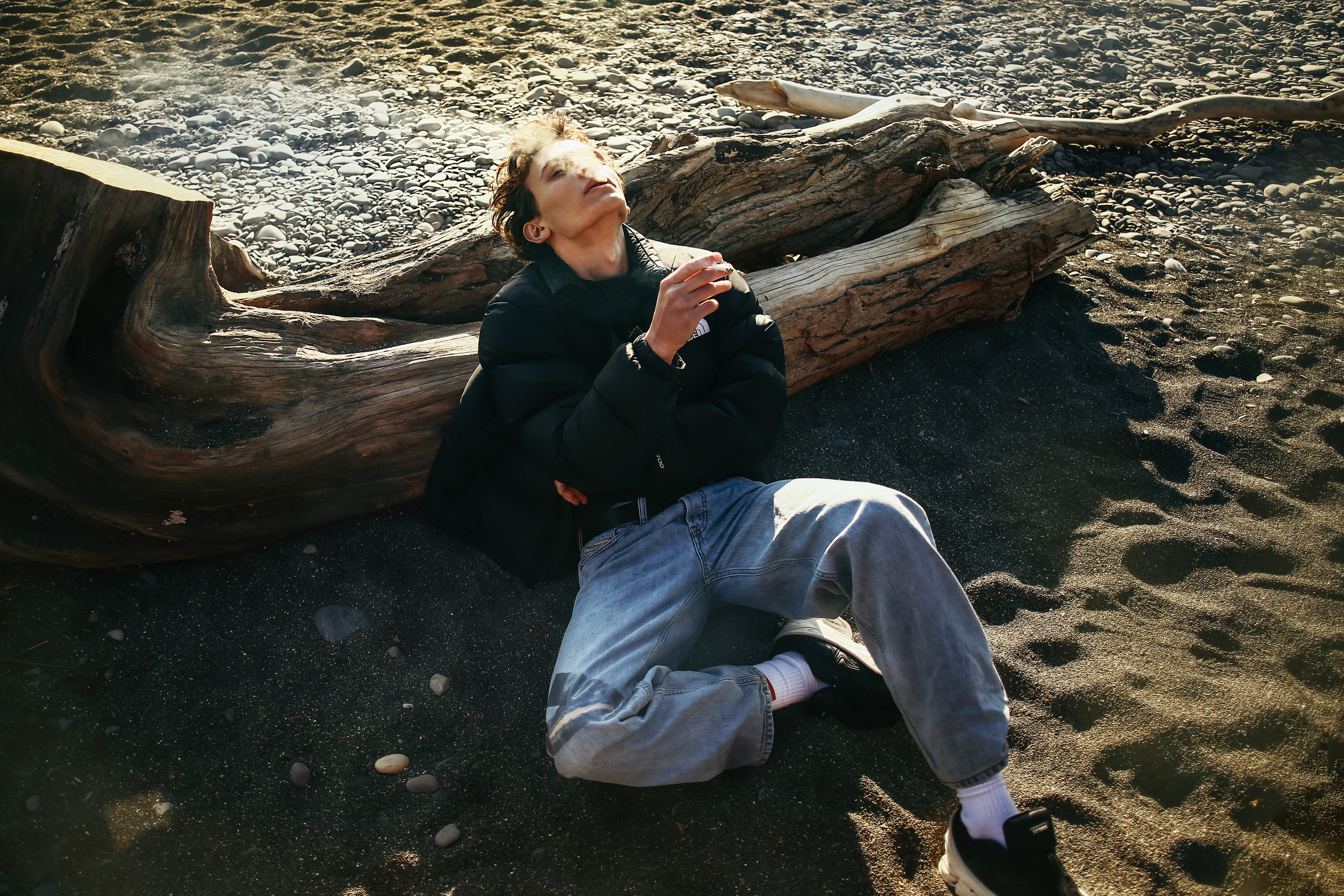 Мужчина лежит на песке и курит