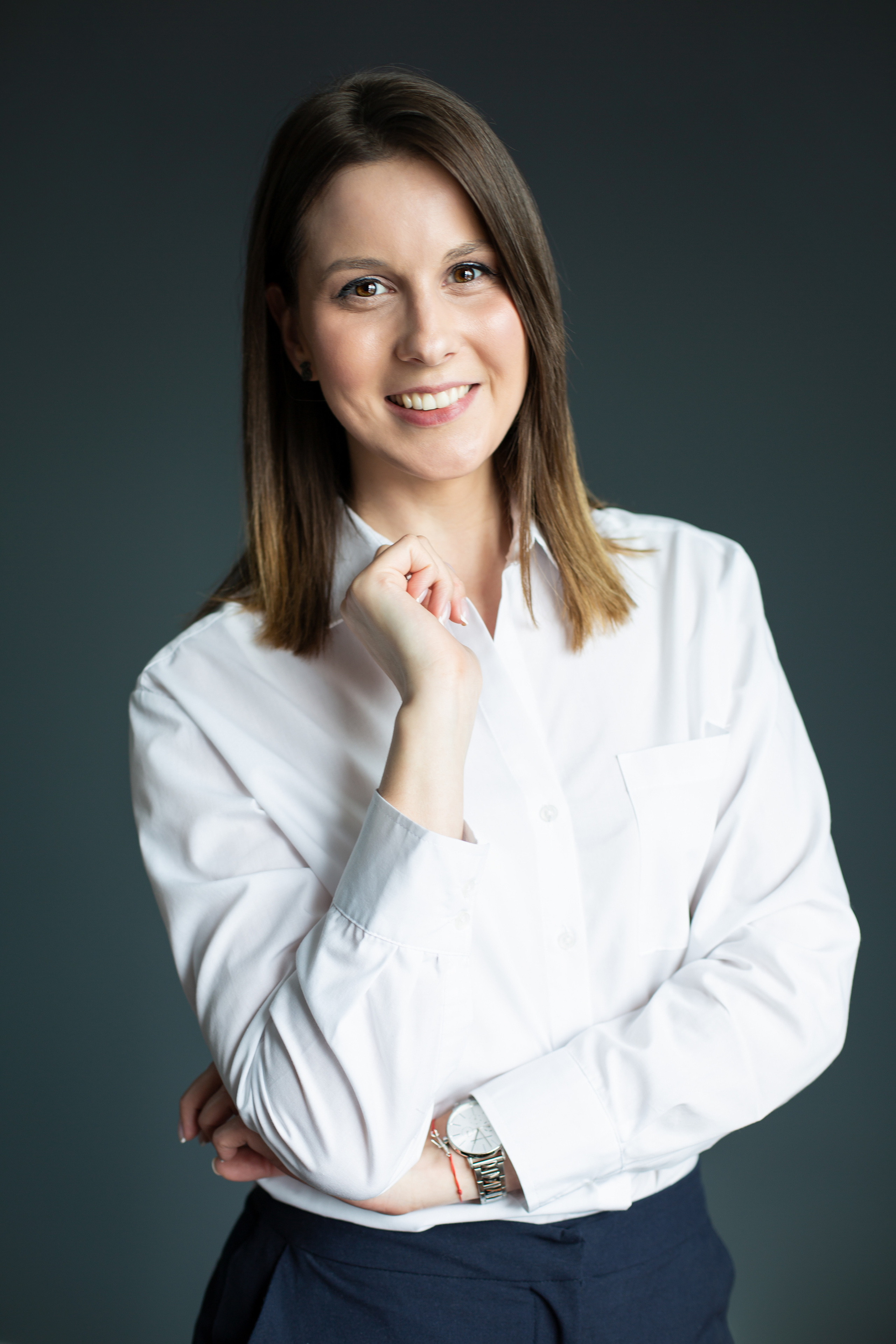 девушка в белой блузке смотрит в кадр и улыбается