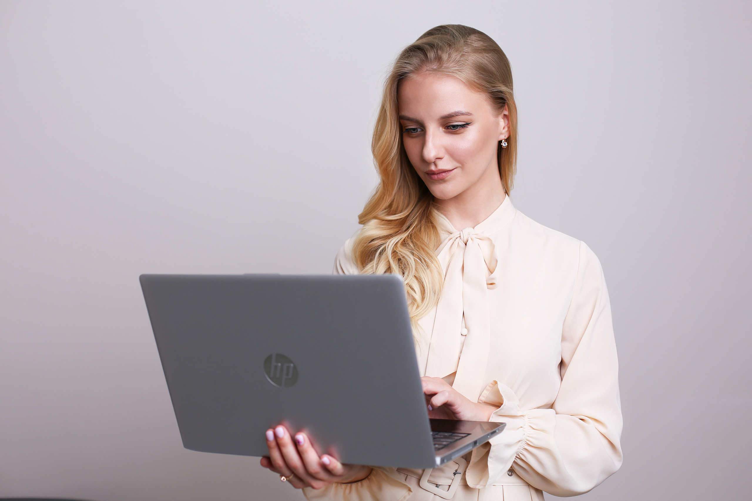 Блондинка с ноутбуком стоит на белом фоне