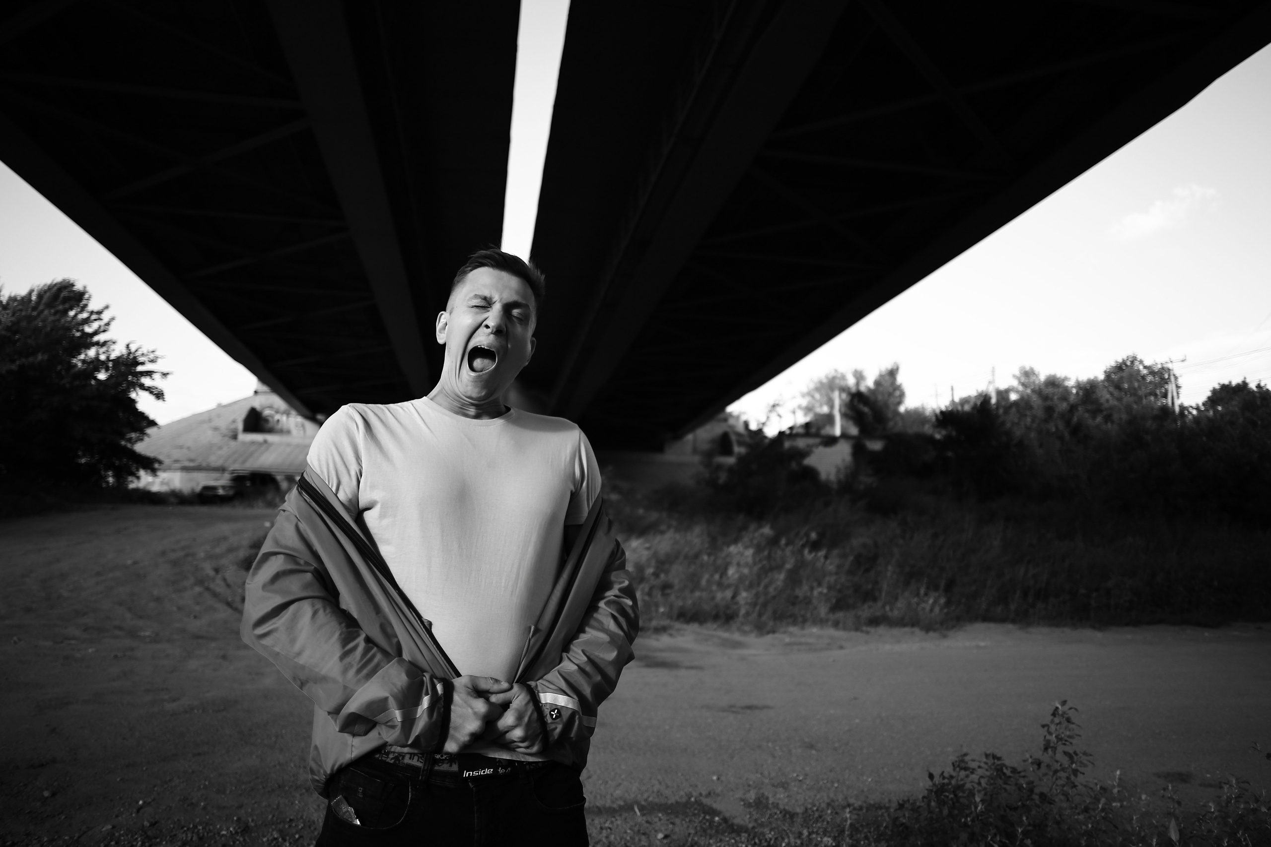 Парень зевает он стоит под мостом 