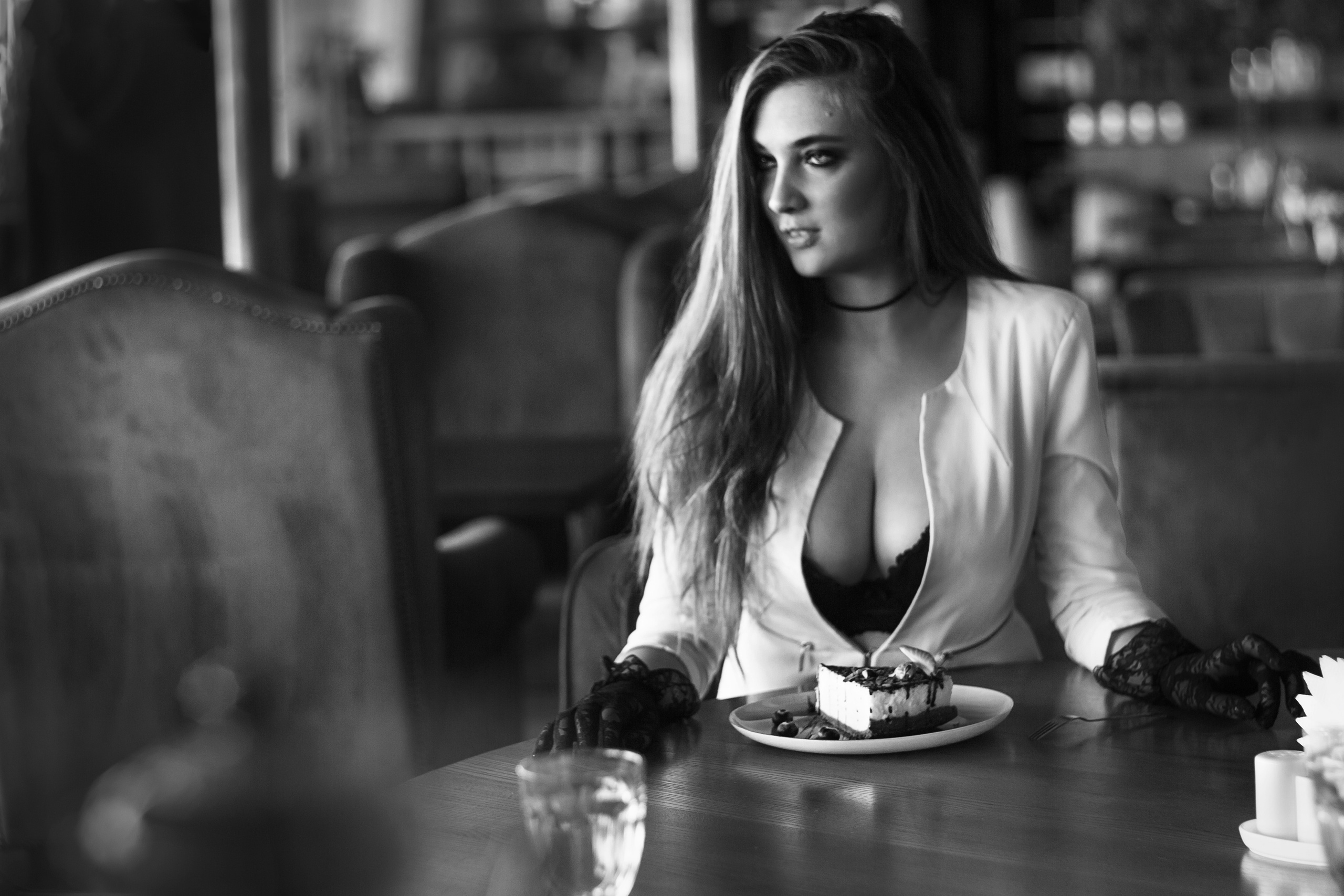 Молодая девушка  с большой грудью сидит за столиком в кафе 