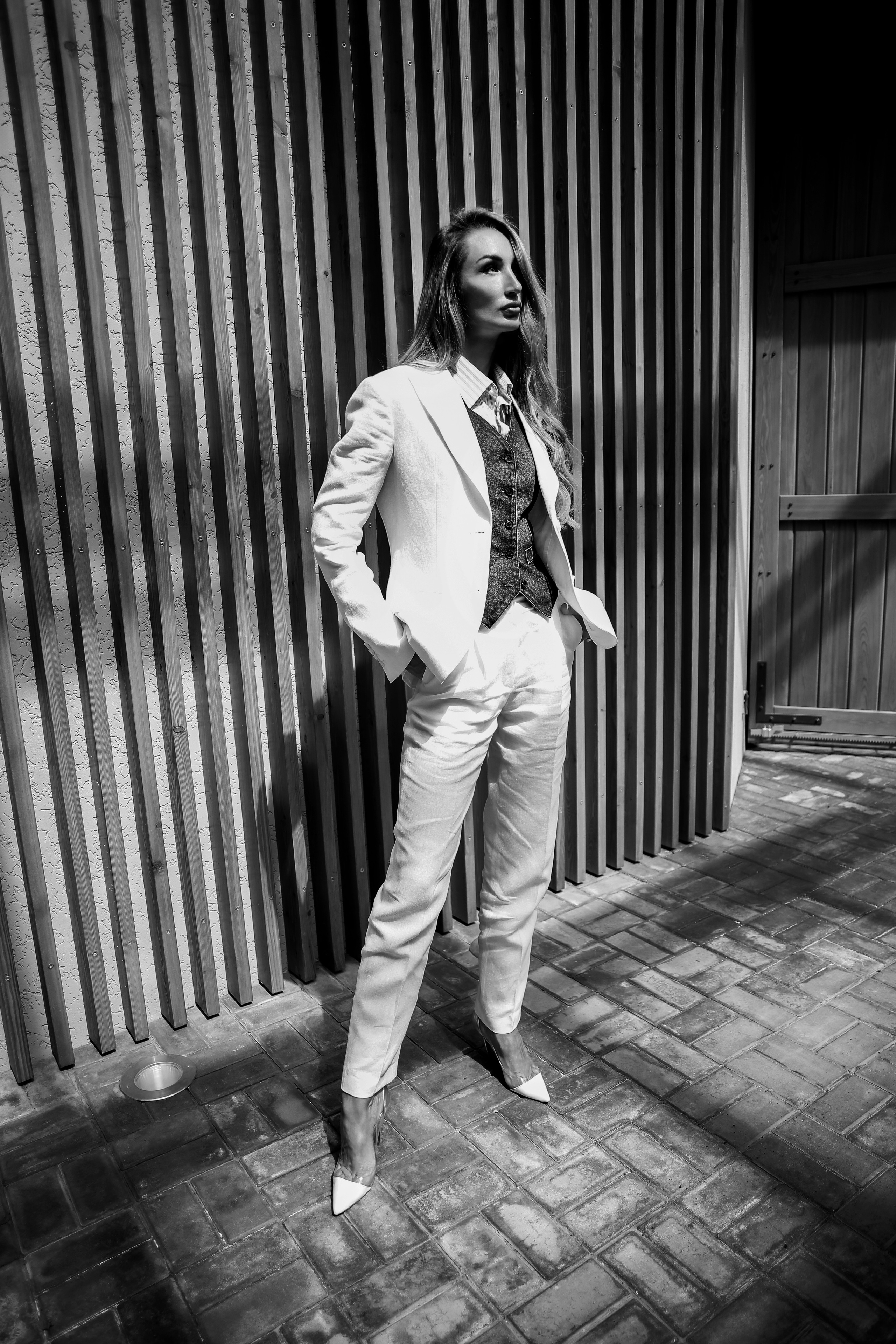 Девушка стоит в красивом белом брючном костюме. Черное белое фото