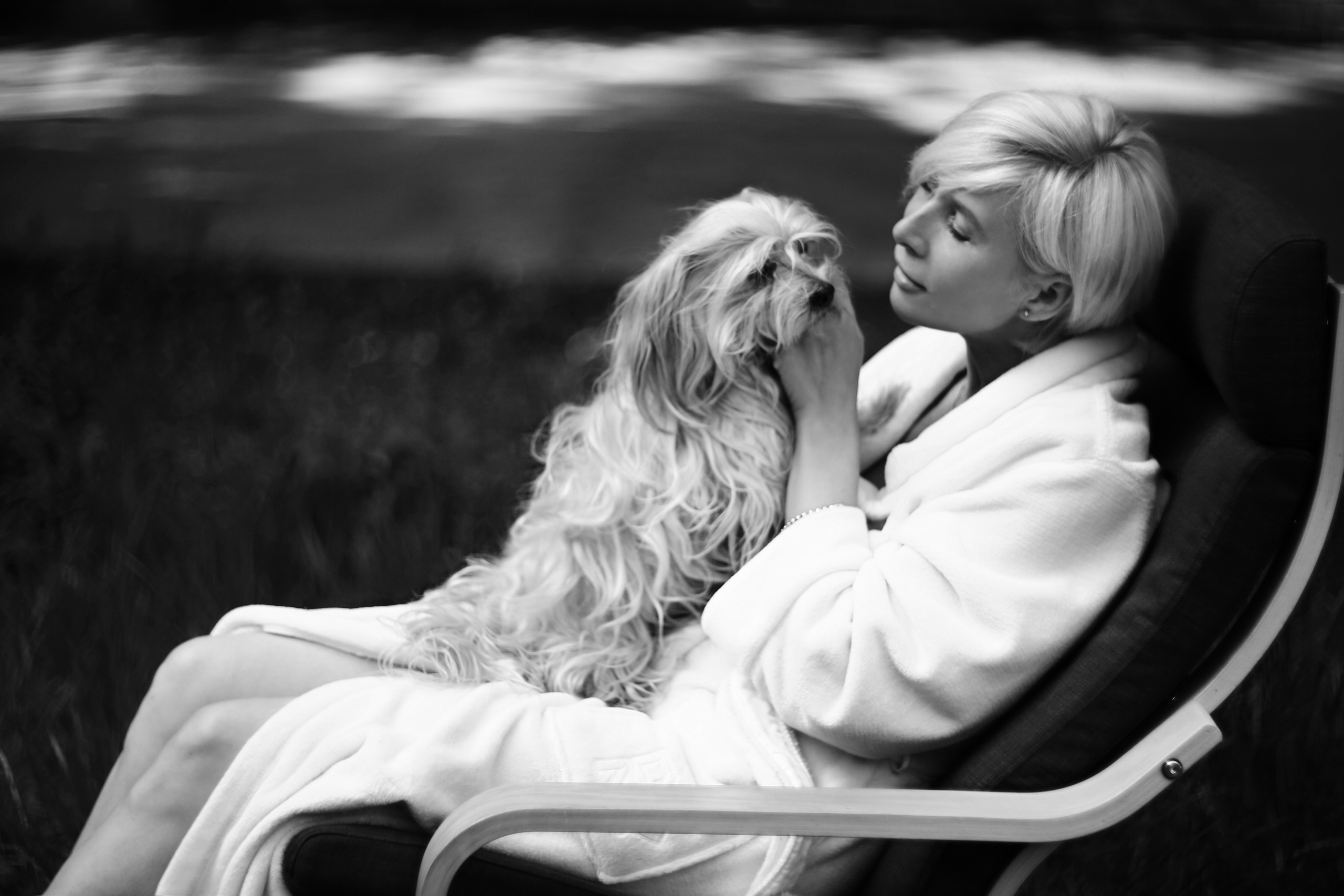 девушка играет с псом в кресле на дачном участке