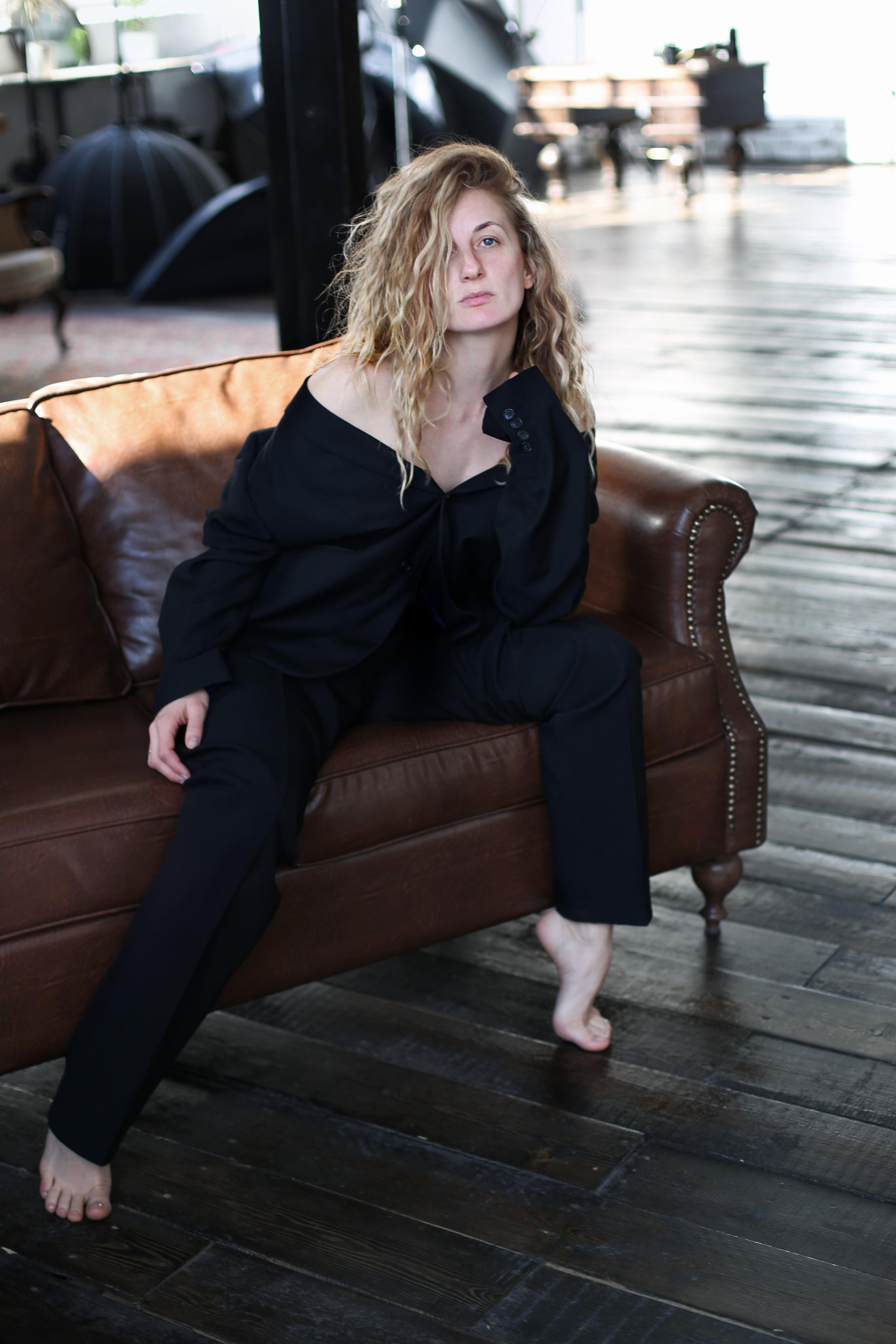 молодая женщина сидит на кожаном диване 