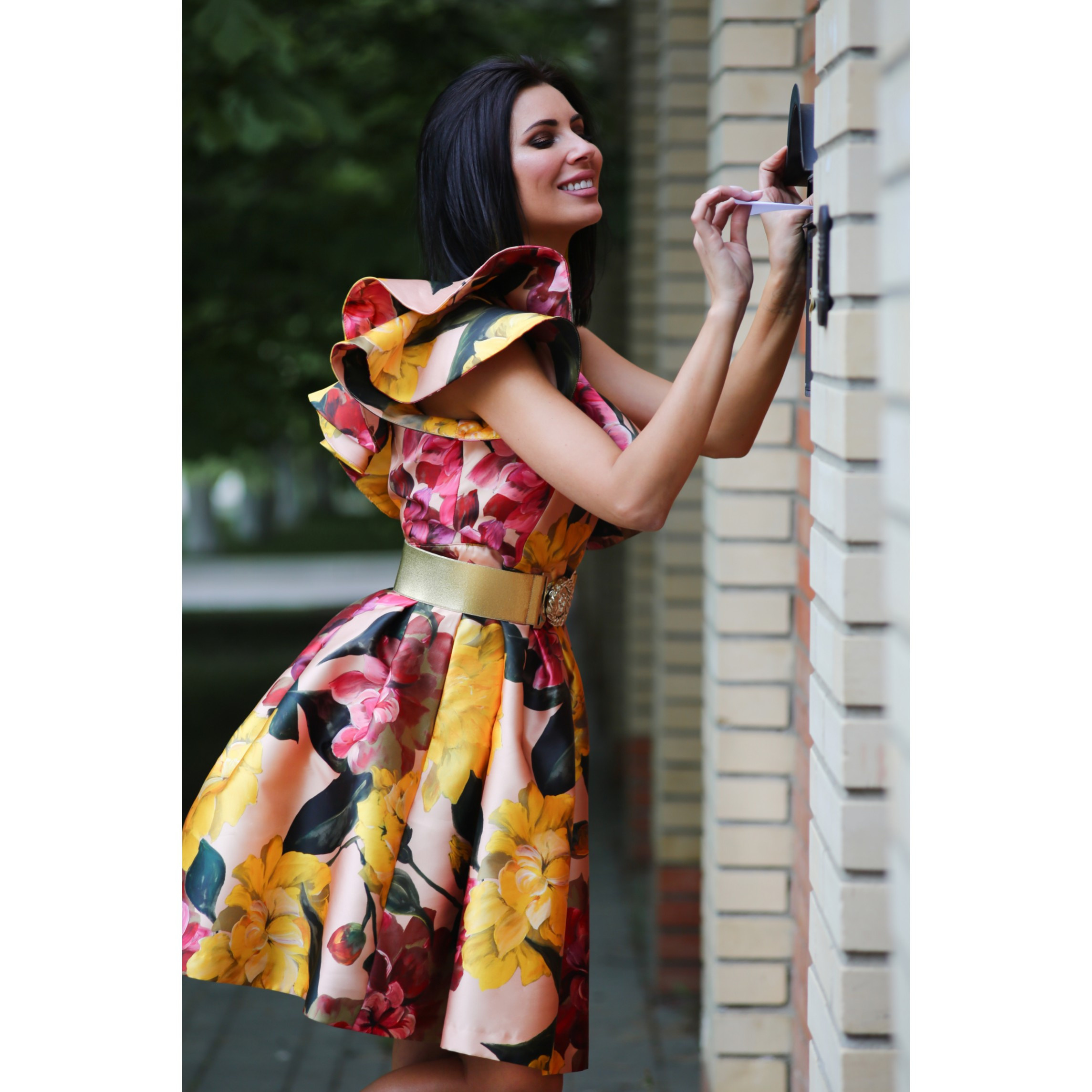 Брюнетка в красивом ярком платье улыбается