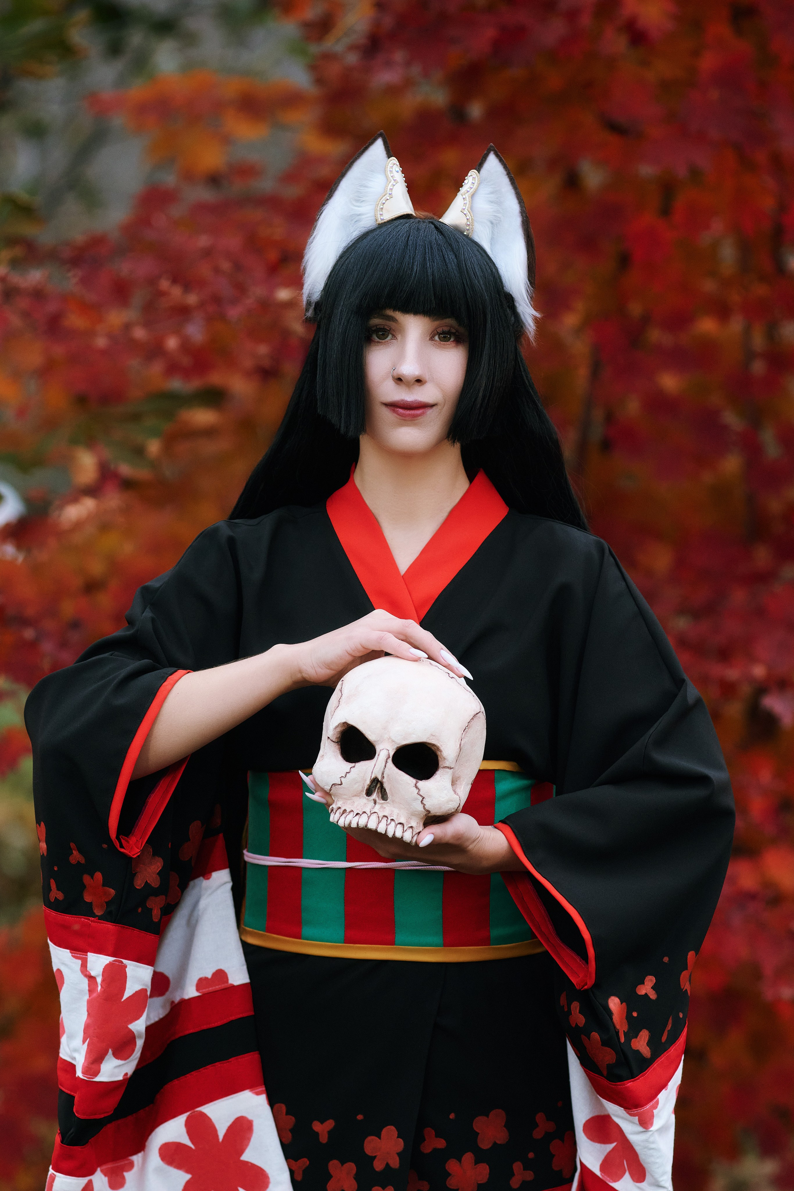 Косплей кицунэ в японском саду с девушкой, держащей череп в руках