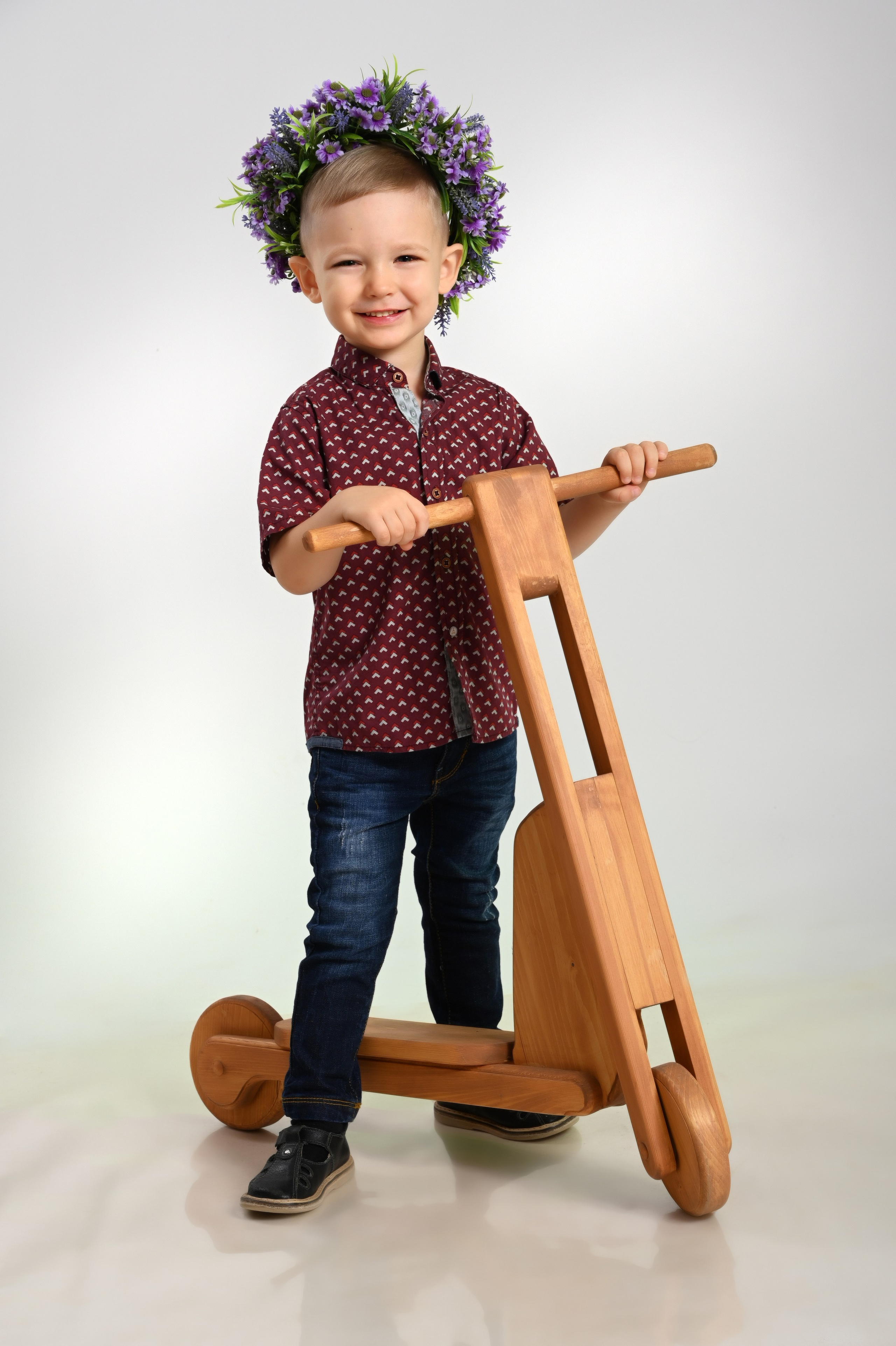 Мальчик выпускник детского сада в Вологде в бардовой рубашке с деревянным самокатом улыбается