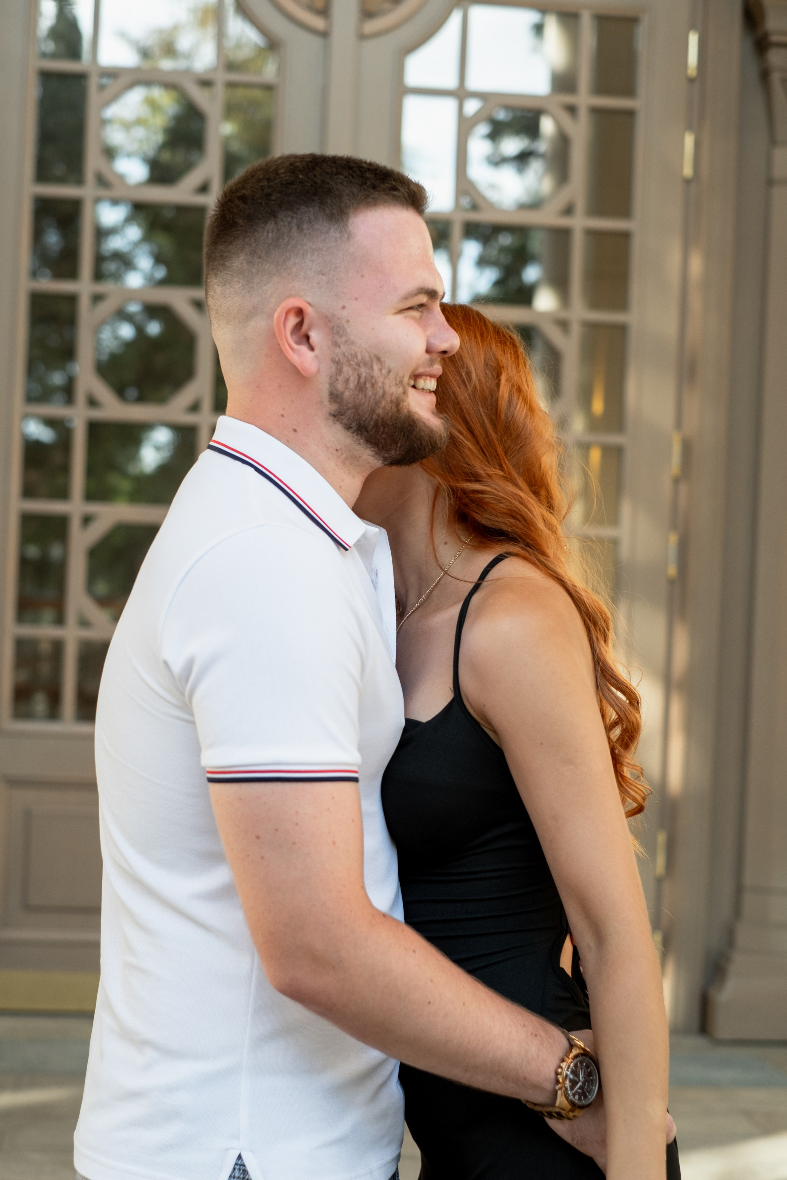 Парный портрет парень обнимает свою рыжую девушку и смотрит вдаль улыбаясь