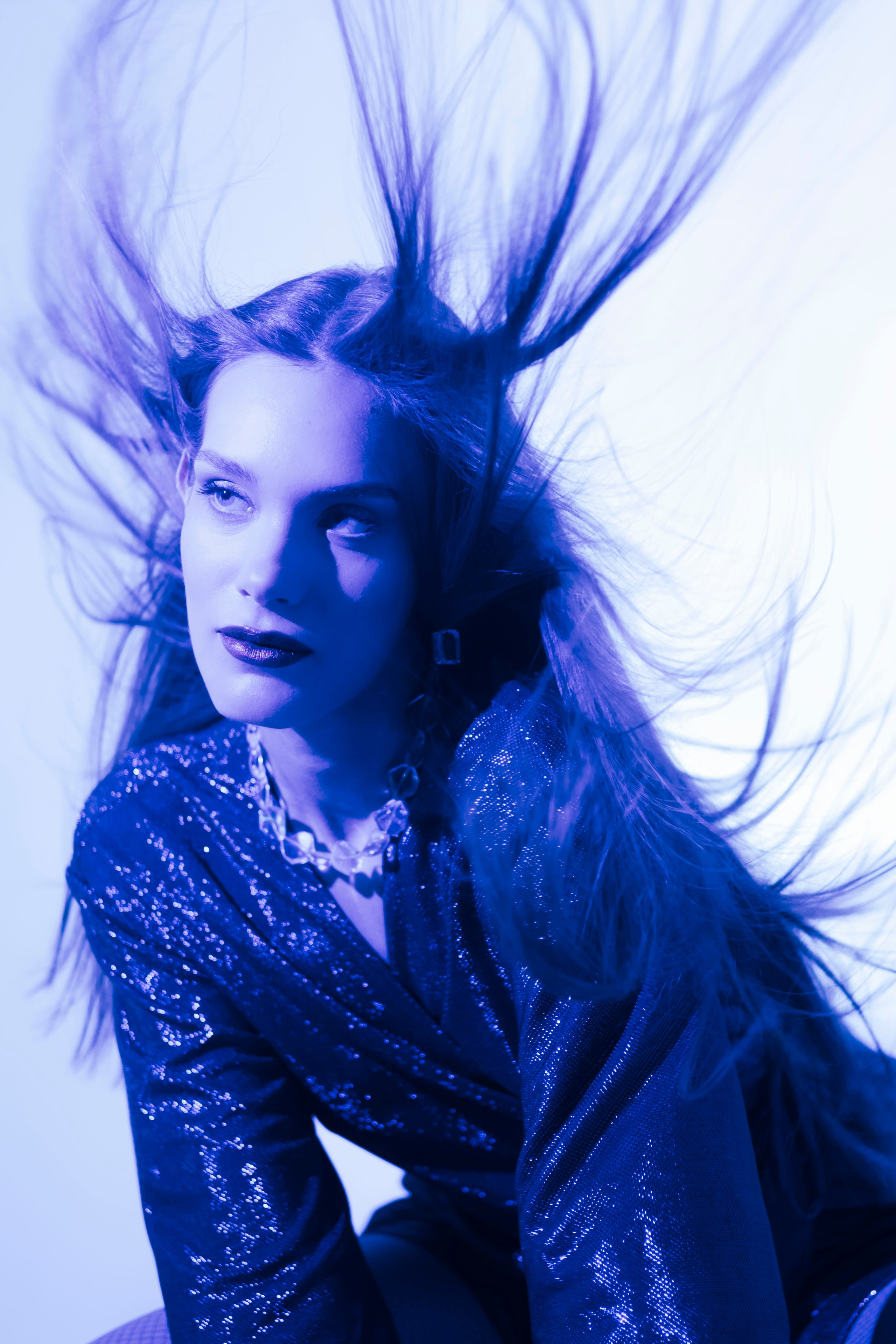 Студийный портрет девушки с вентилятором и цветным светом