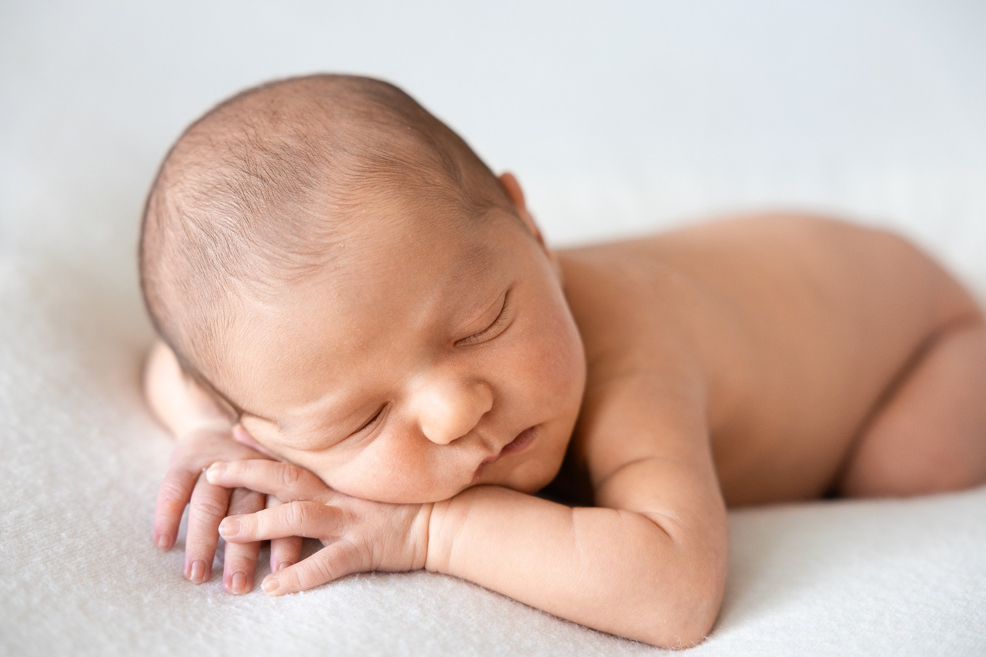 Младенец спит на животике, подложив ручки под щечку.