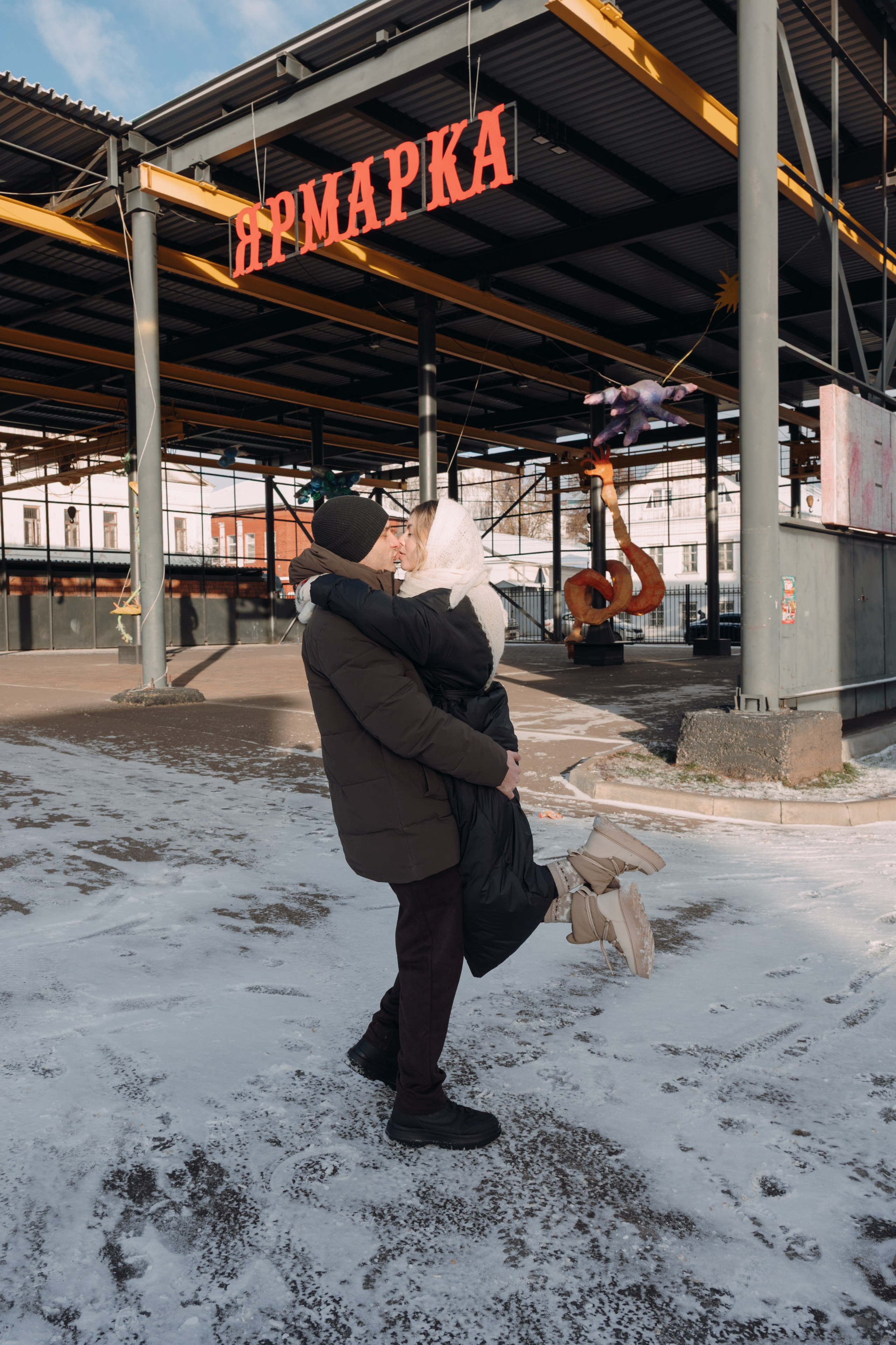 мужчина поднял девушку на руки в зимнем городе 