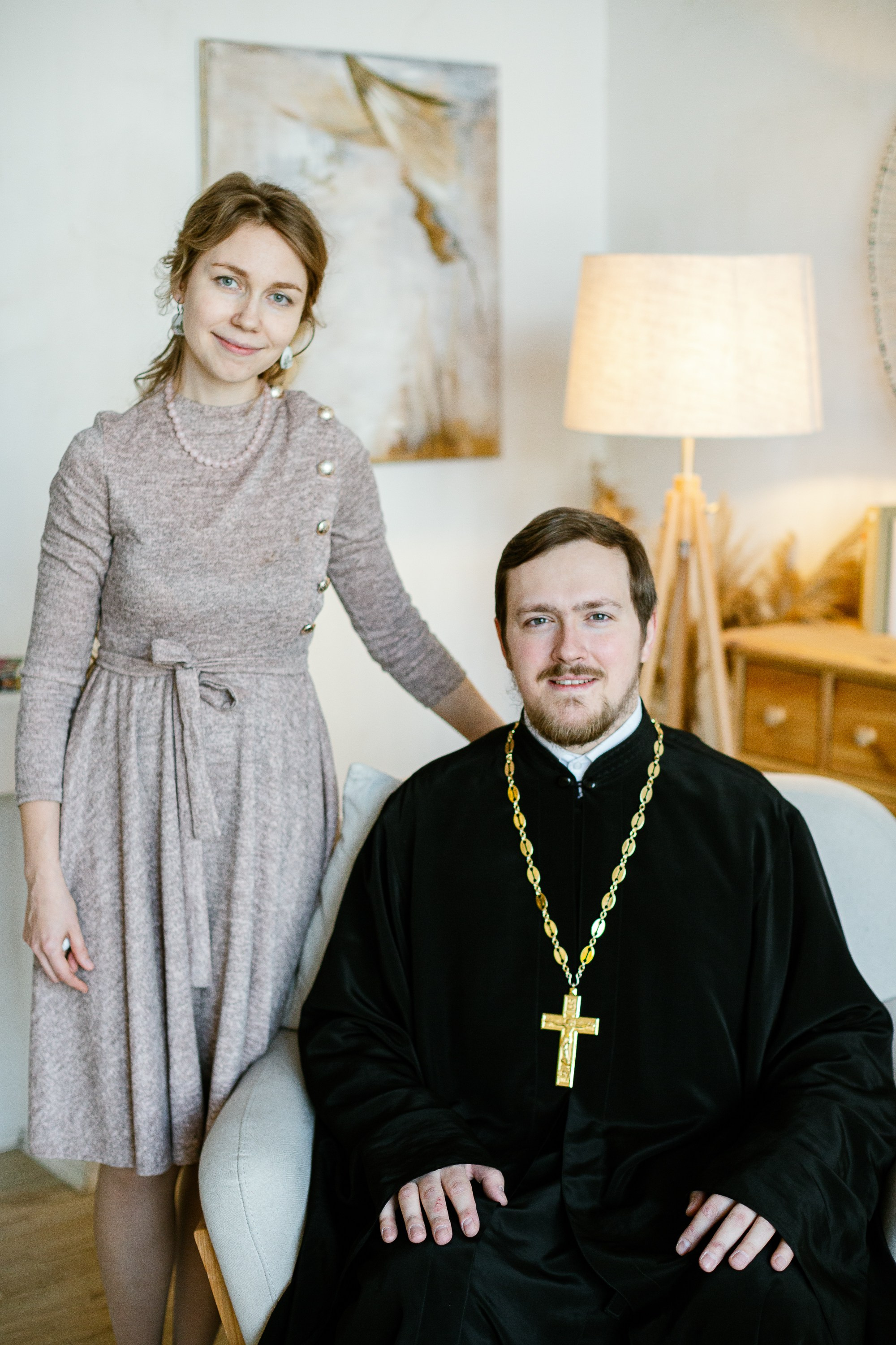 Семья священника. Муж сидит на кресле, жена стоит возле него.