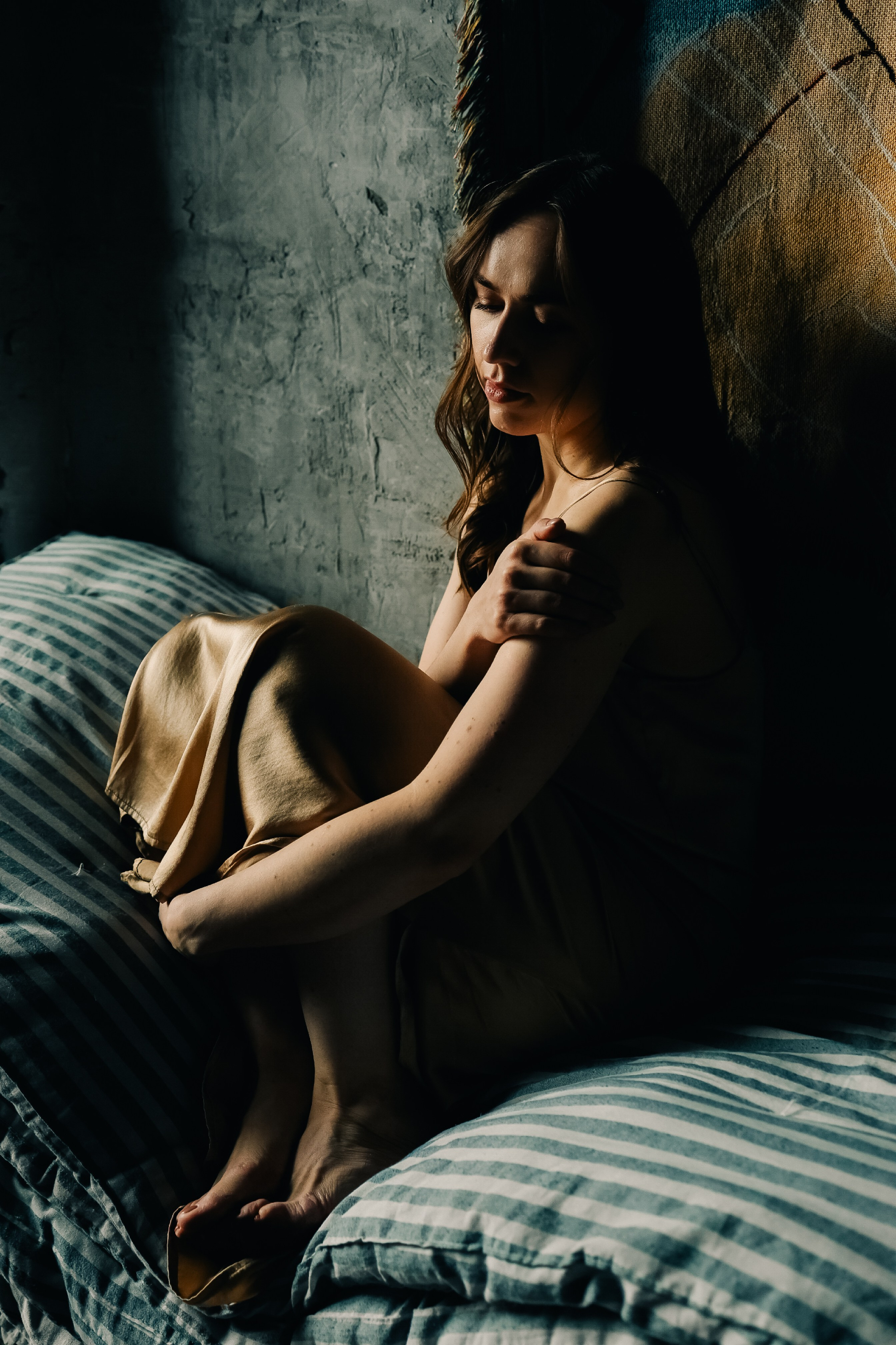 Одинокая девушка сидит на матрасе