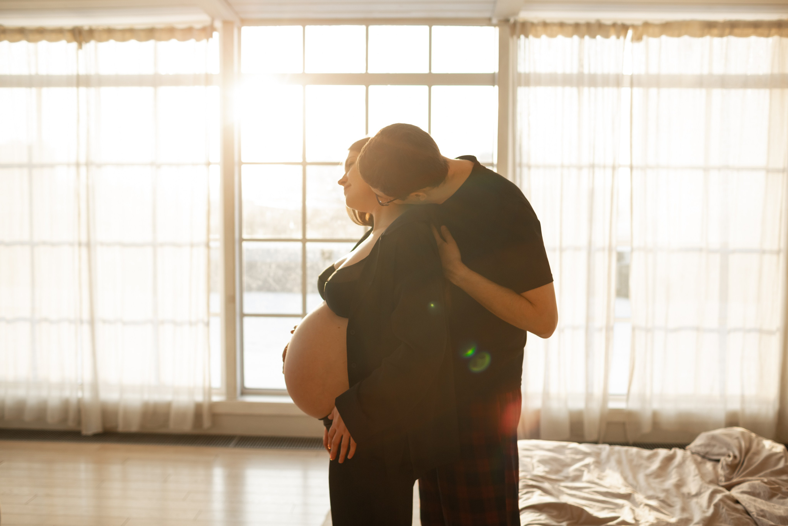 Муж обнимает и целует в шею беременную жену