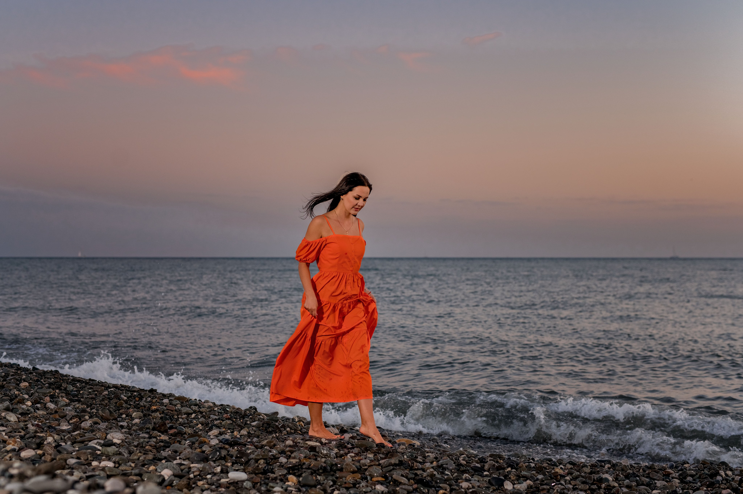 девушка на закате в ярком платье на берегу Черного моря в Сочи