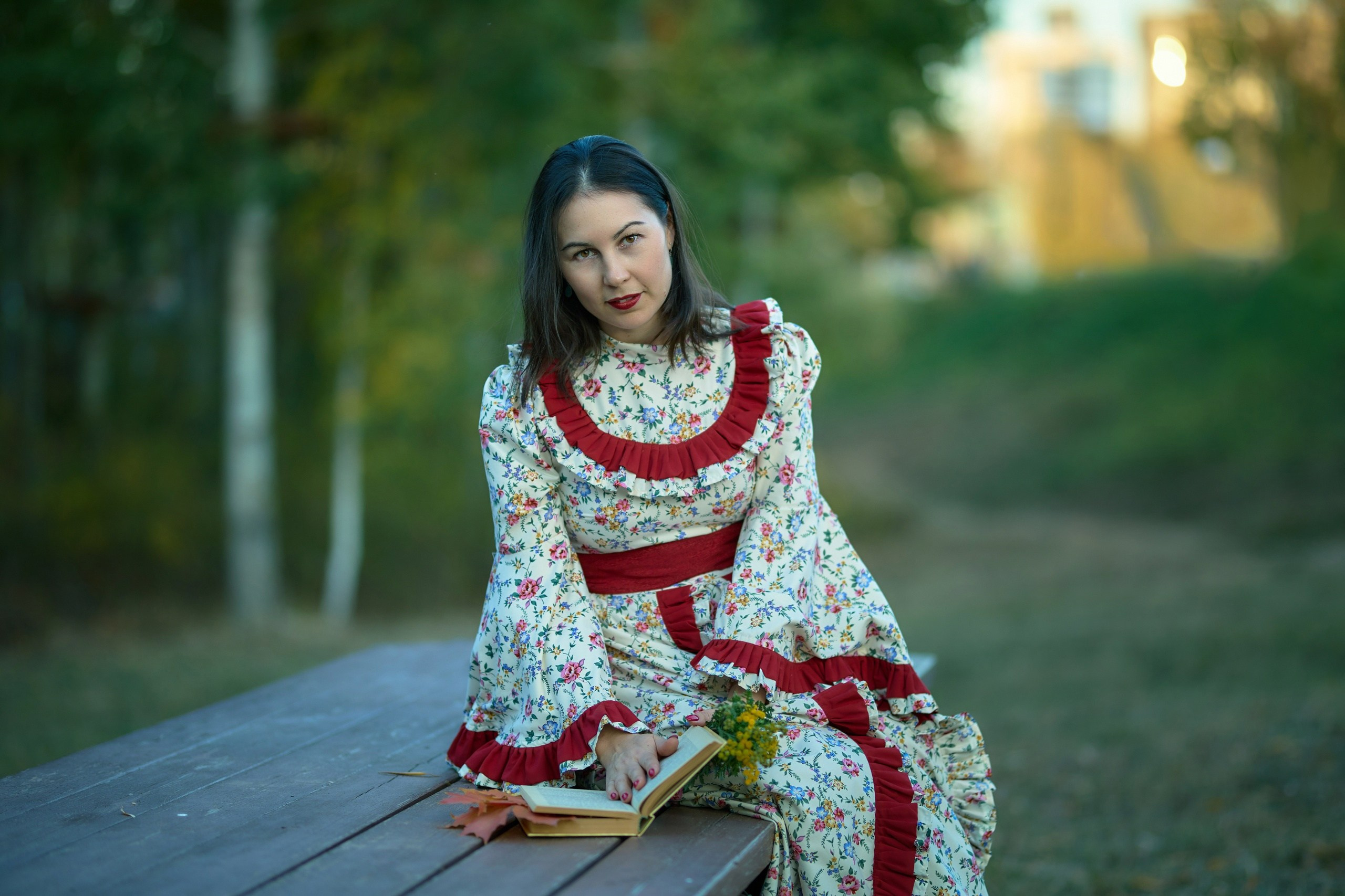 Женщина с книгой в руках сидит на скамейке