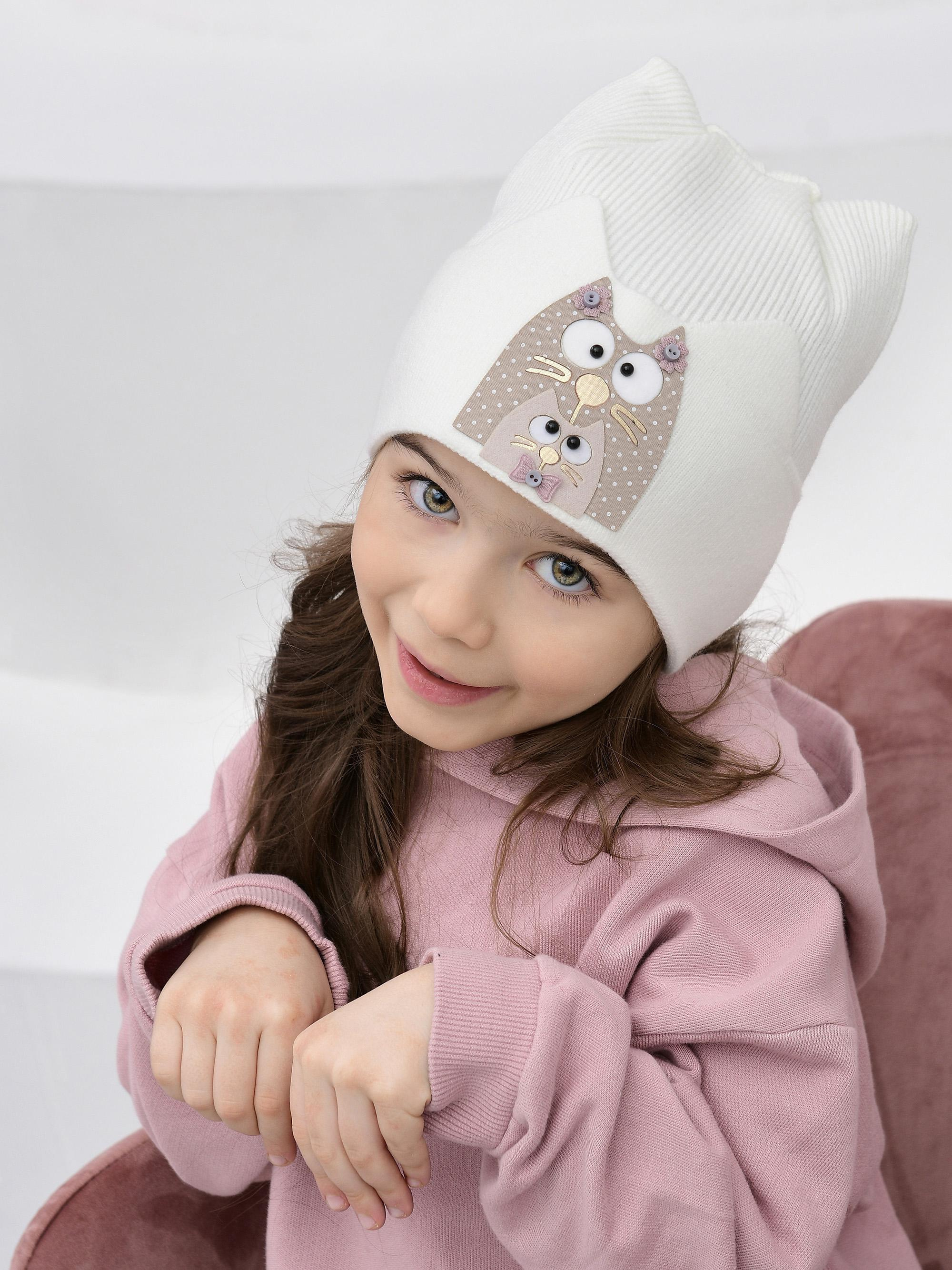 Белая детская шапка на модели в фотостудии.