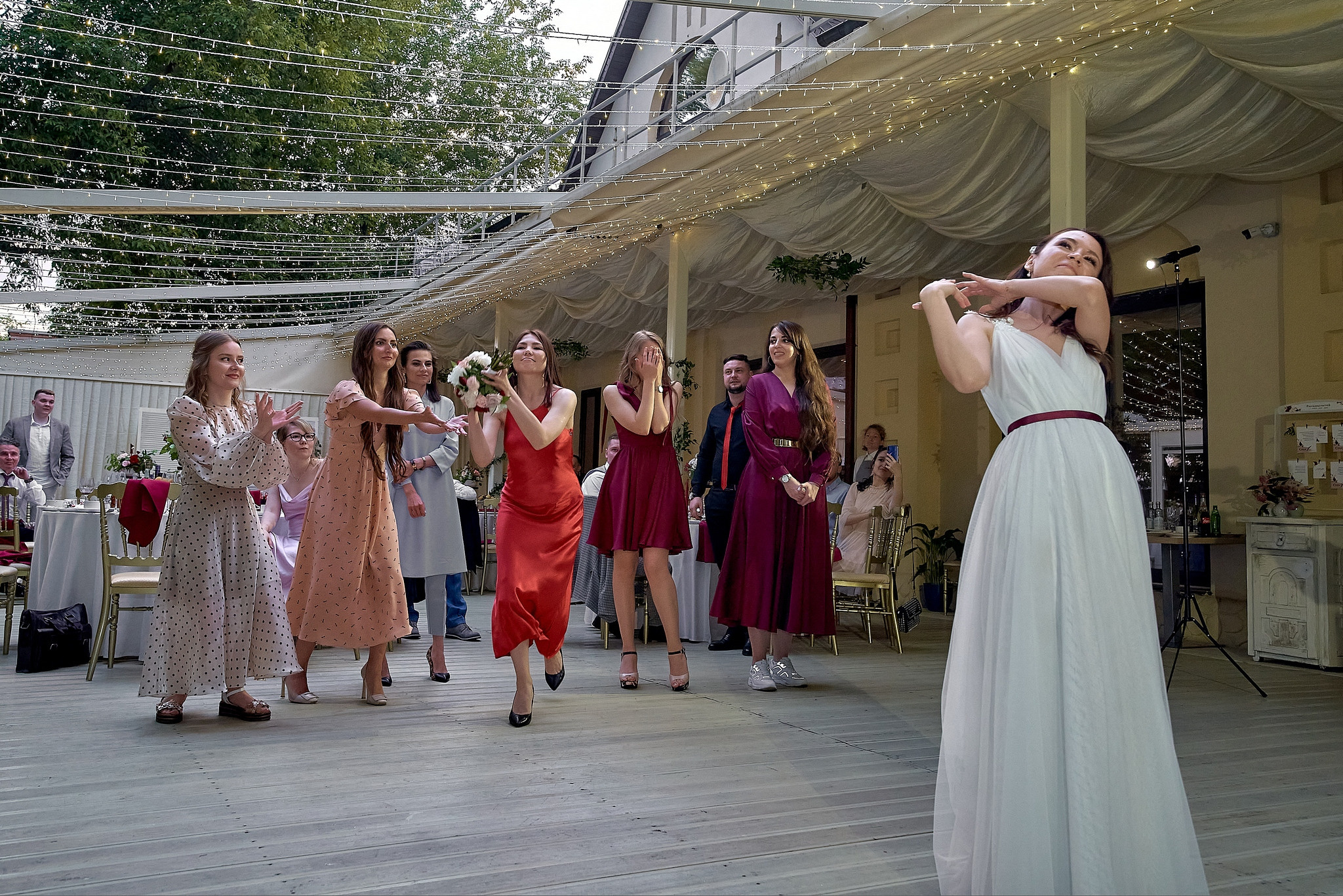 Невеста бросает букет подругам на свадебном банкете.  Свадебный фотограф на свадьбу в Москве Сергей Гаварос. gavaros.ru