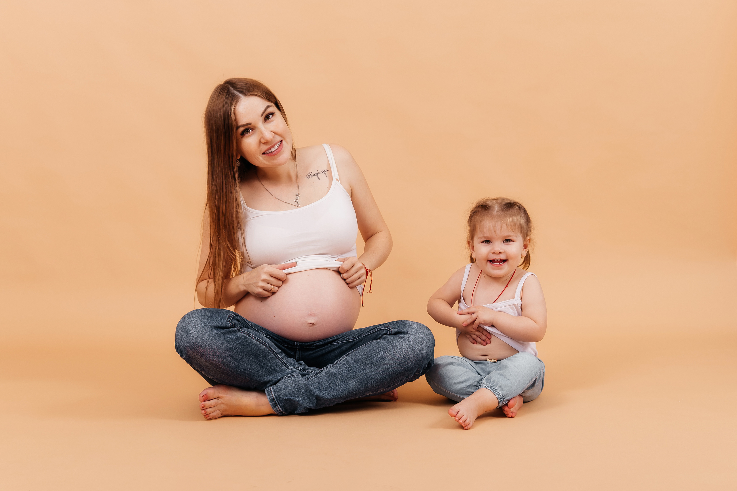 Беременная девушка  в джинсах смеются с ребенком