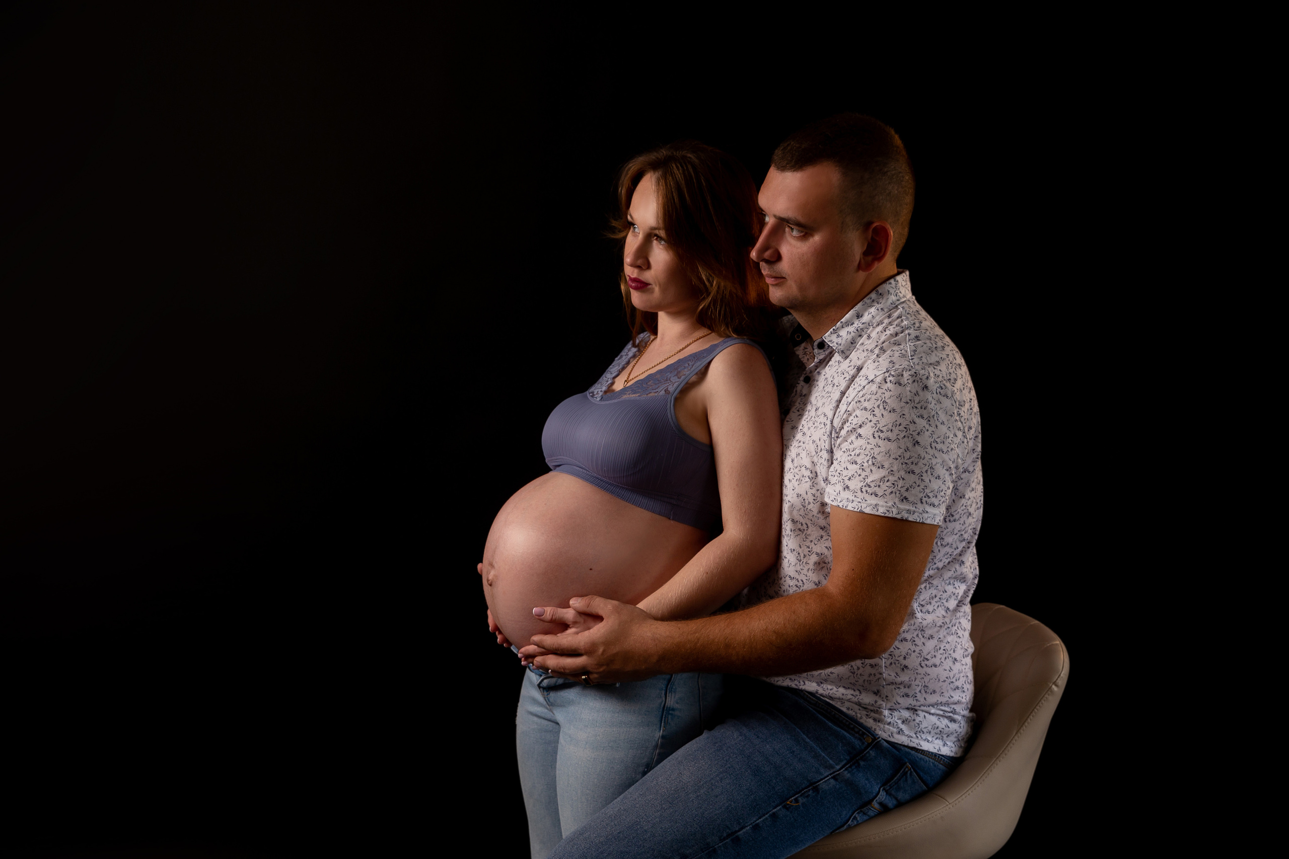 Беременная девушка с мужем на черном фоне