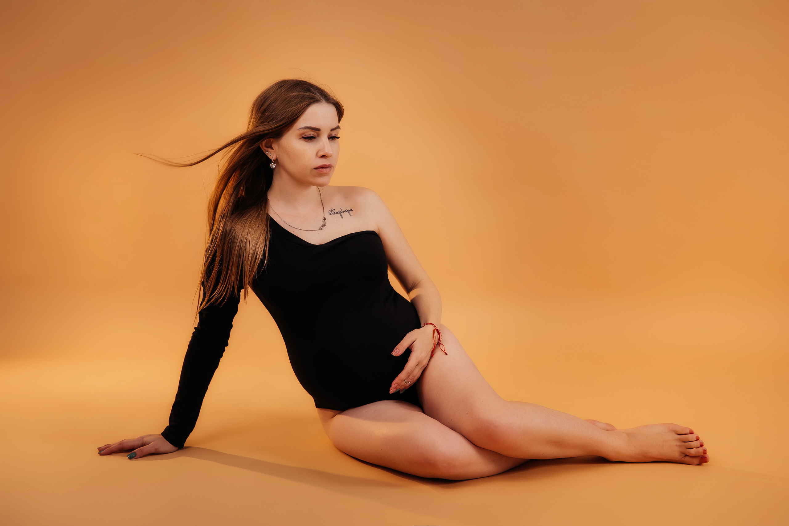 Беременная девушка  в боди на светлом фоне