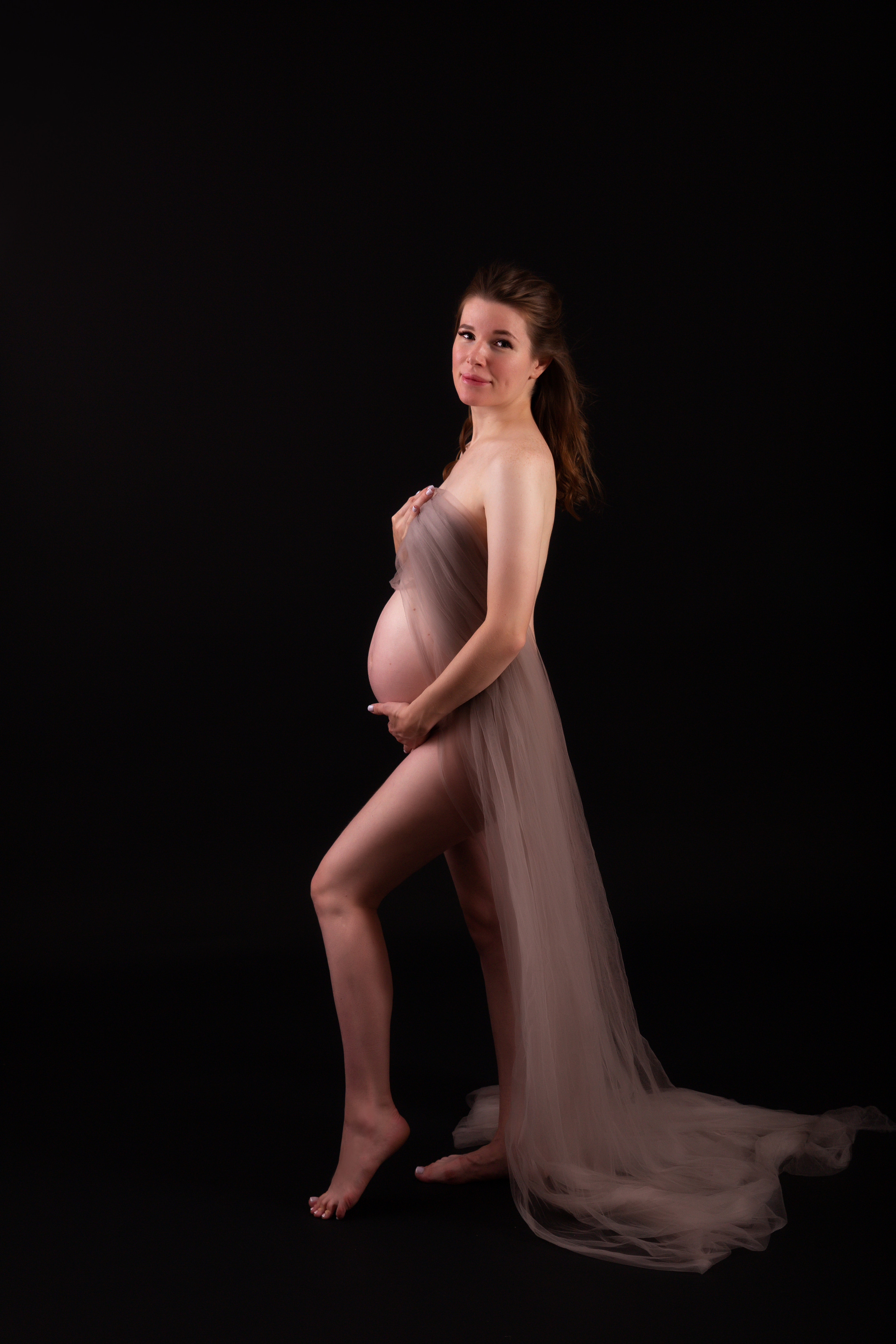 БеременнБеременная девушка  на темном фоне в тканиая девушка  в боди