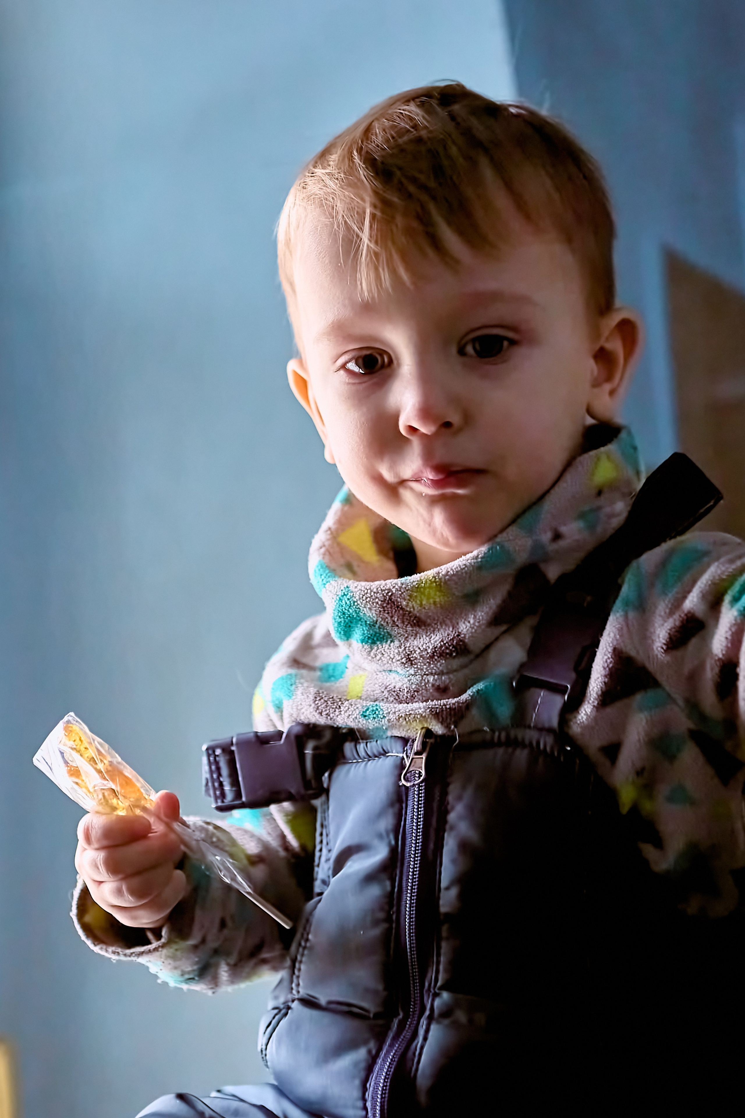 Малыш со сладкой карамелью петушком у окна в Храме