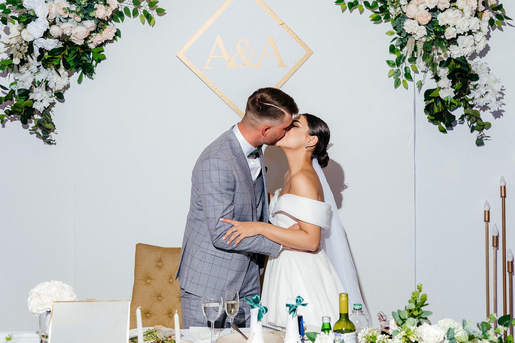 Молодожены целуются на фоне президиума.