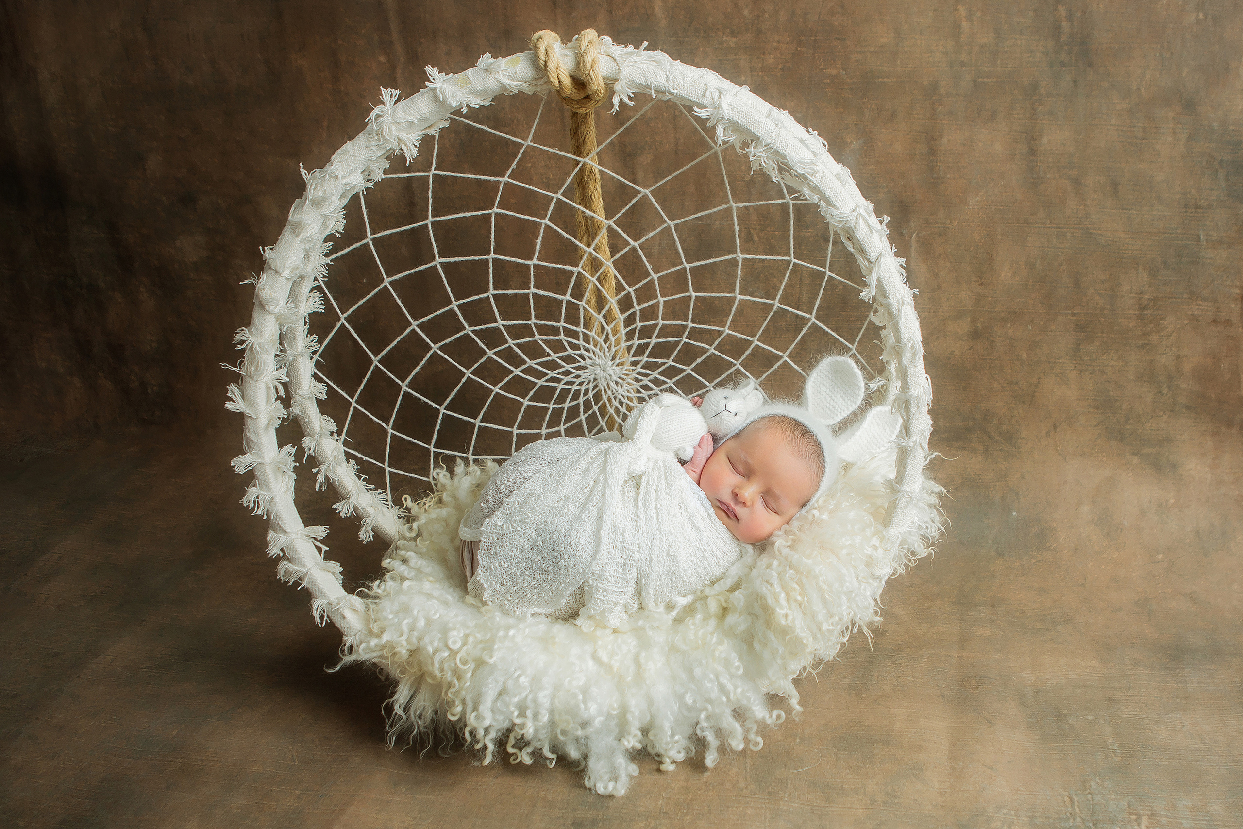 новорожденный малыш в корзинке с магическим талисманом индейцев ловцом снов на коричневом фоне 