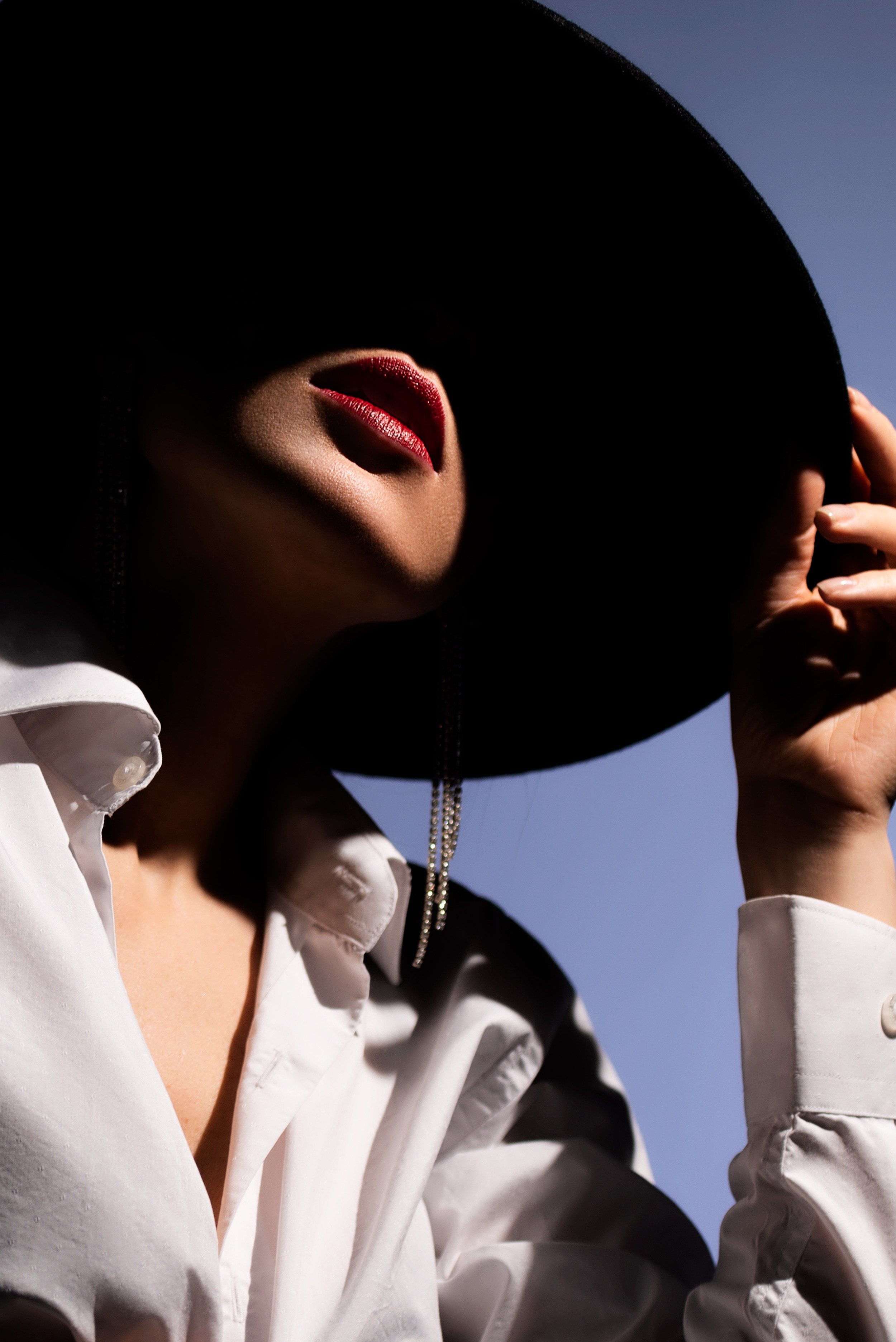 Крупный портрет девушки в черной шляпе, светом выделены яркие красные губы