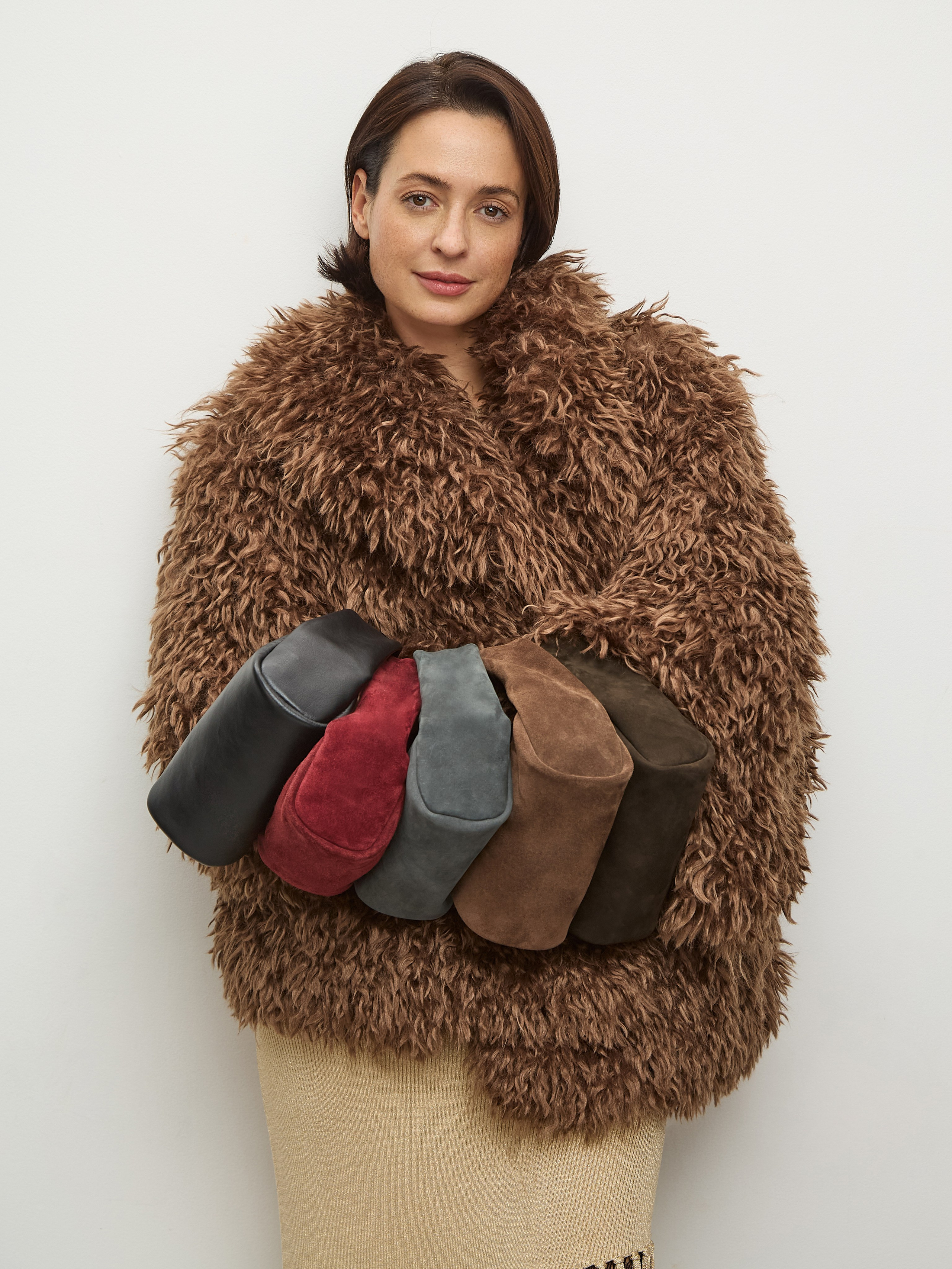 Женщина в современной искусственной шубке с несколькими модными сумками