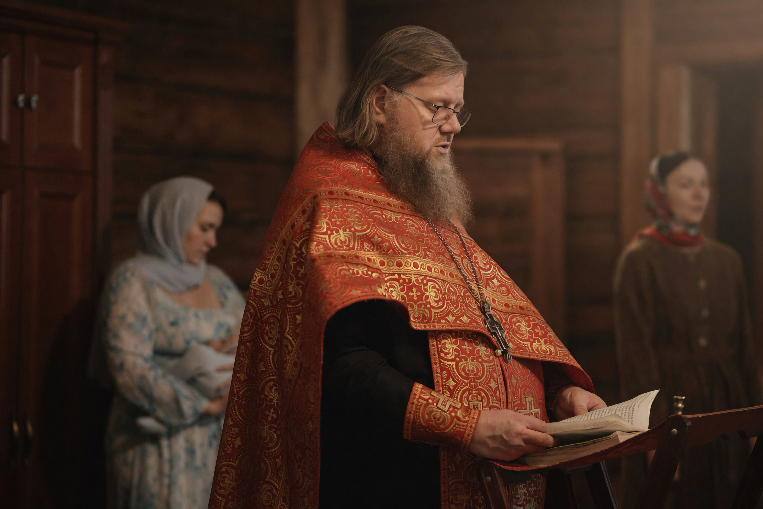 Священник в красном облачении читает молитвы у аналоя, тёплый свет деревянного храма — Екатеринбург, Илья Антропов