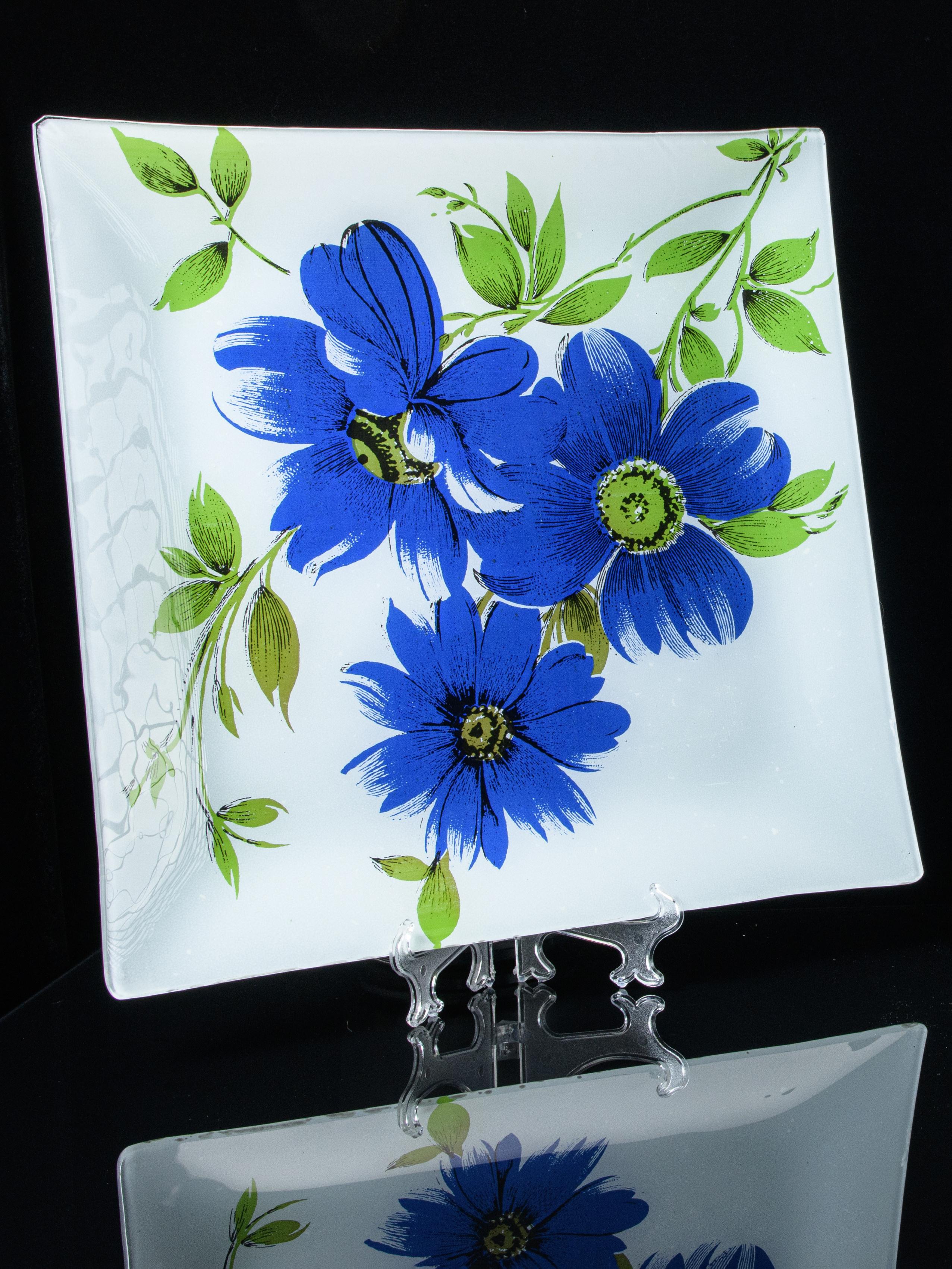 Тарелка с нарисованными синими цветами на подставке с отражением