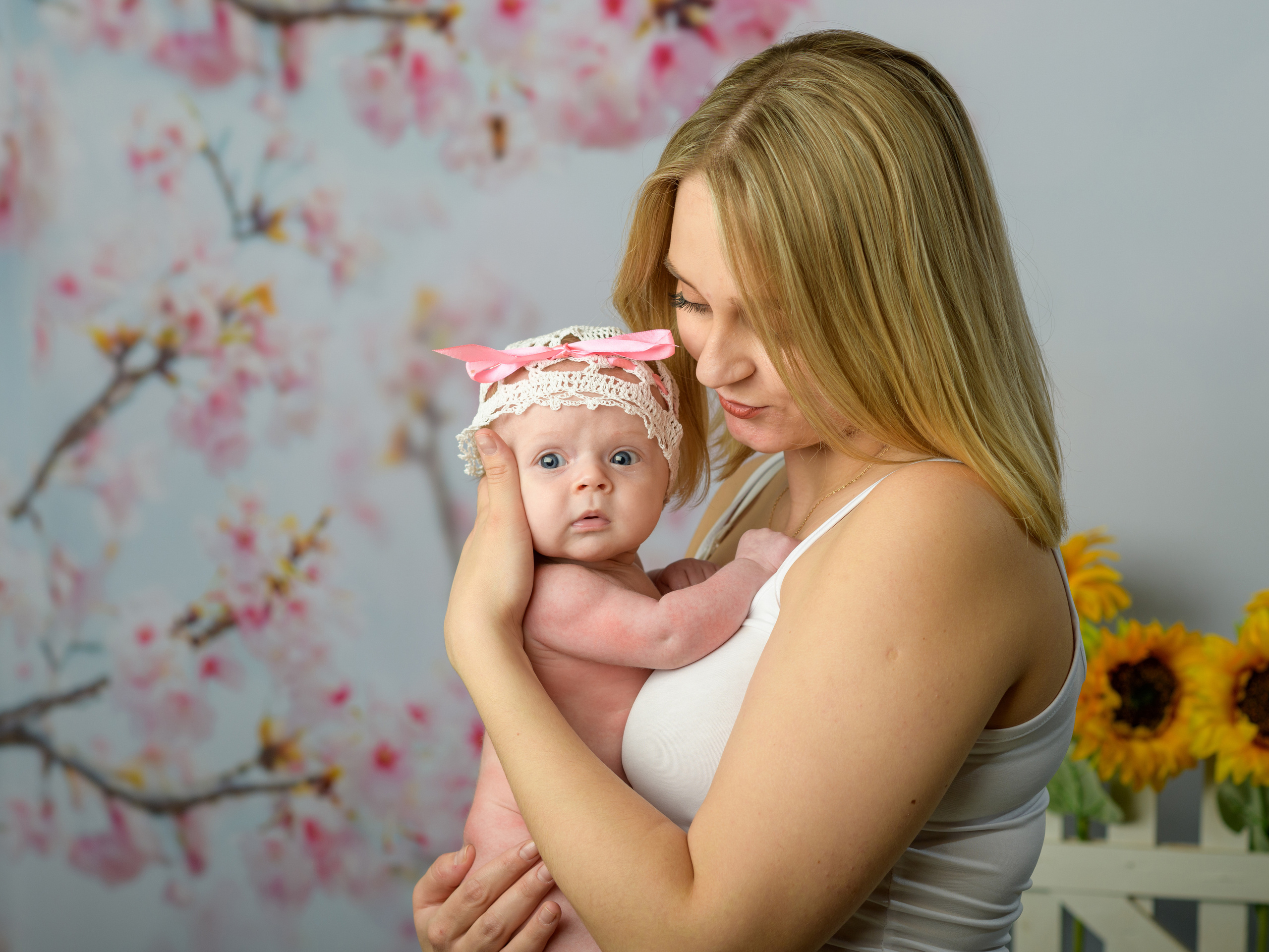 Мама держит на руках маленькую дочку и нежно смотрит на нее