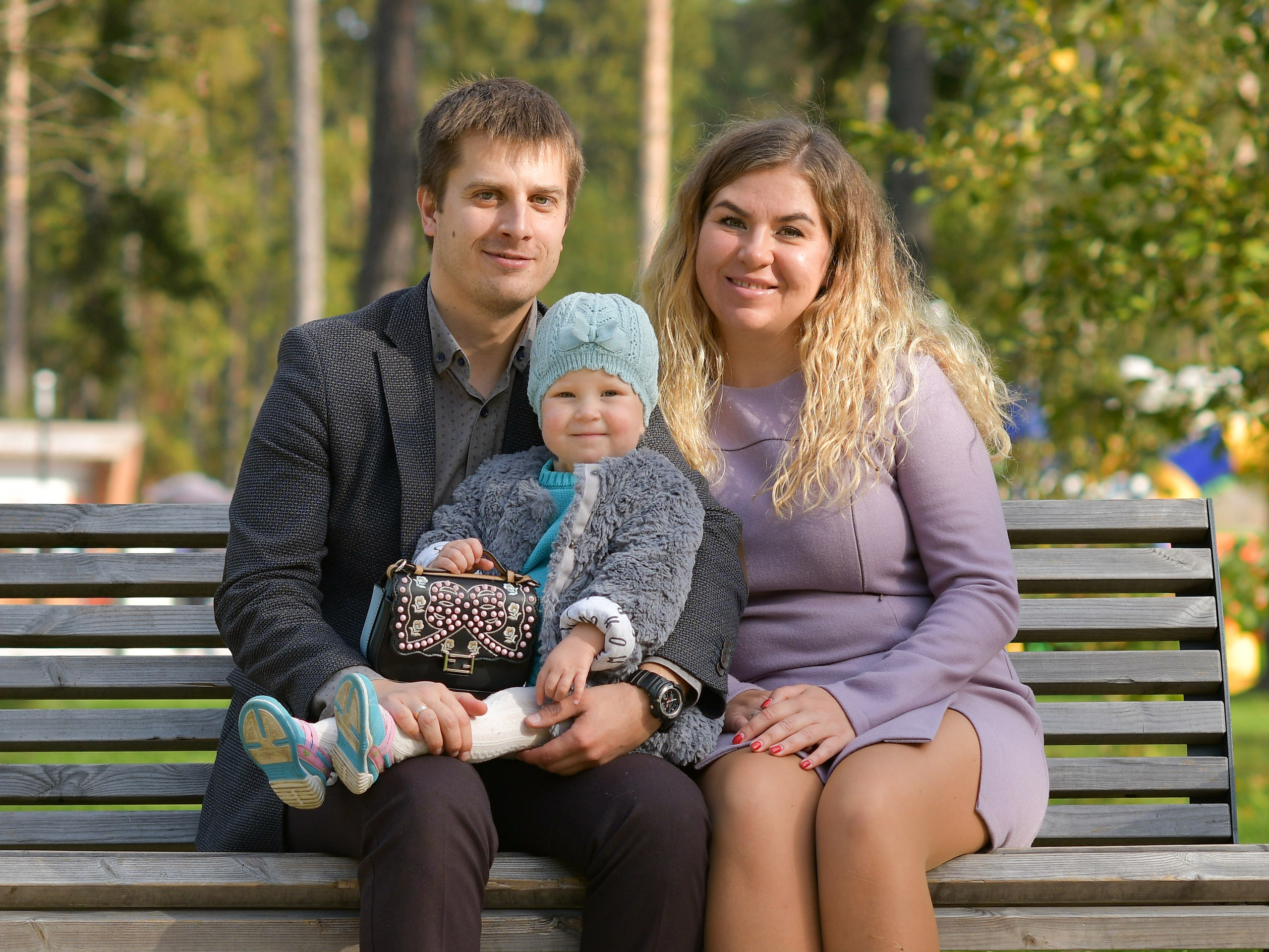 В парке на скамейке сидят родители с ребенком на руках